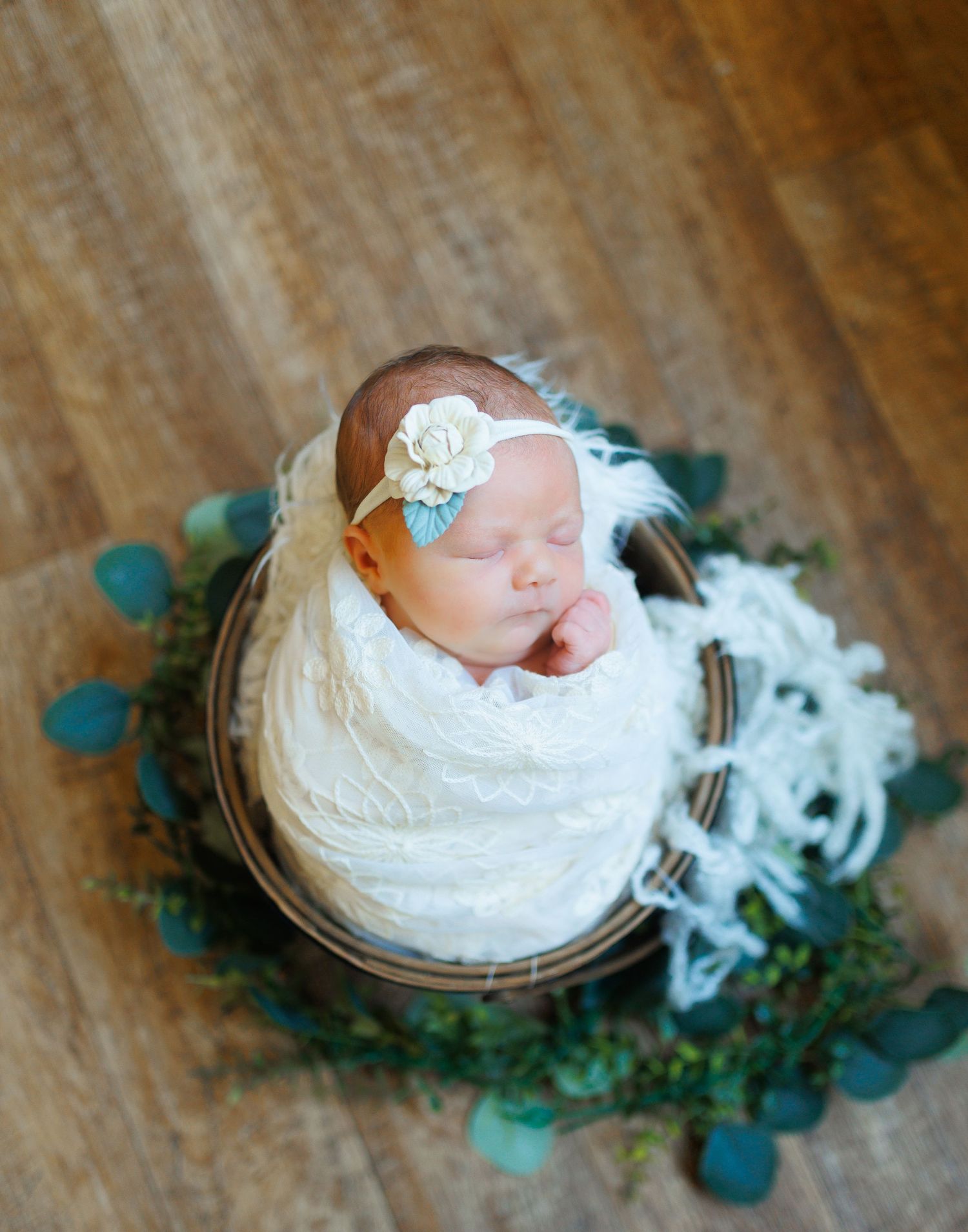 a newborn baby girl wrapped in a pretty white swaddle