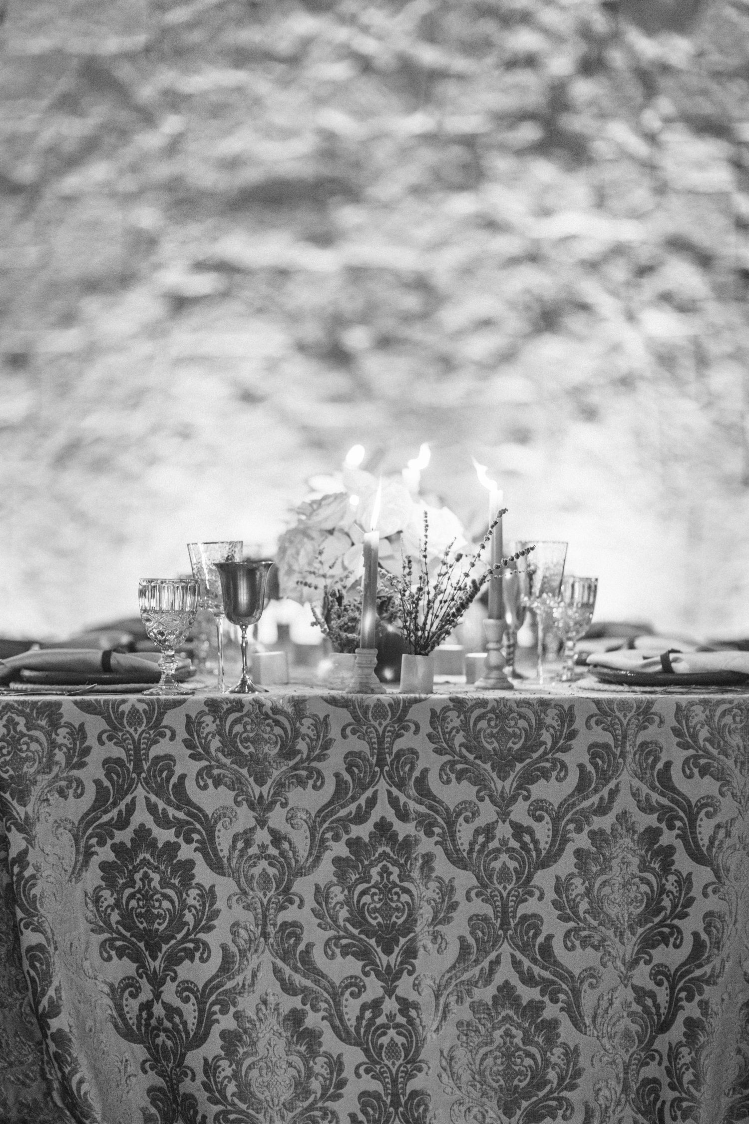 Elegant table setting with damask tablecloth and floral centerpiece in black and white photography.