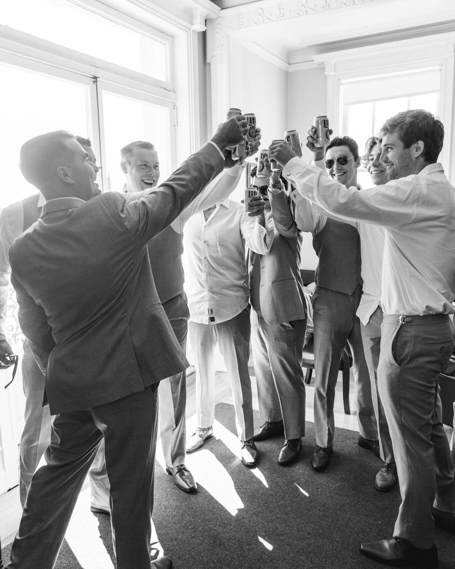Black and white photo of groomsmen raising glasses in celebration.