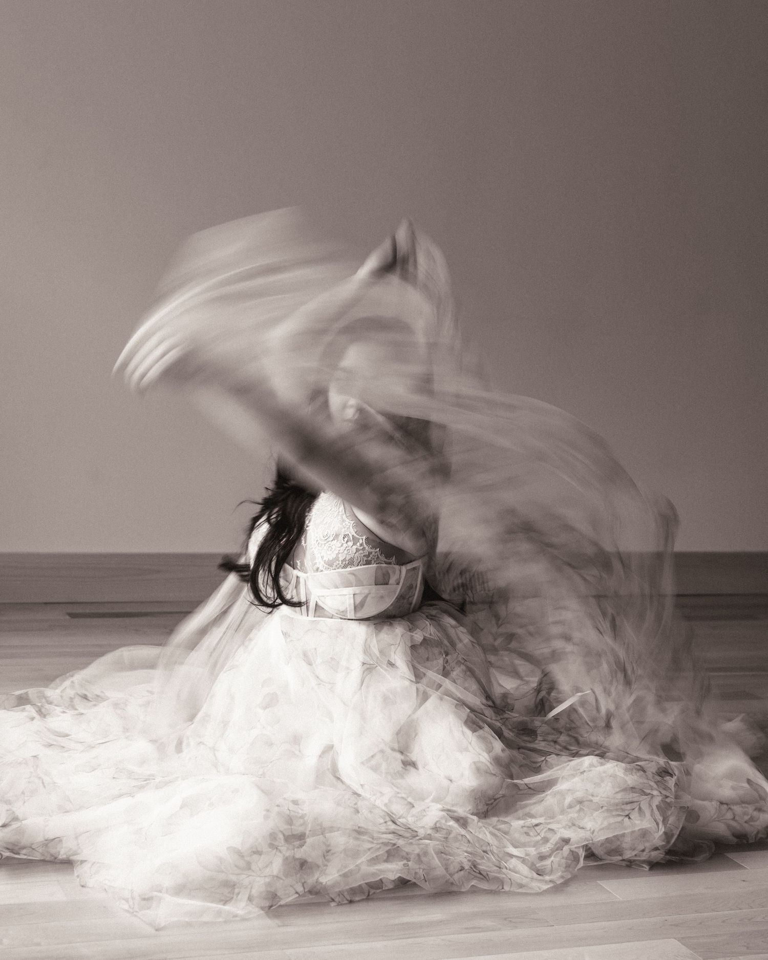 Ethereal black and white photograph of a dancer in a flowing white dress creating motion blur with fabric in motion.