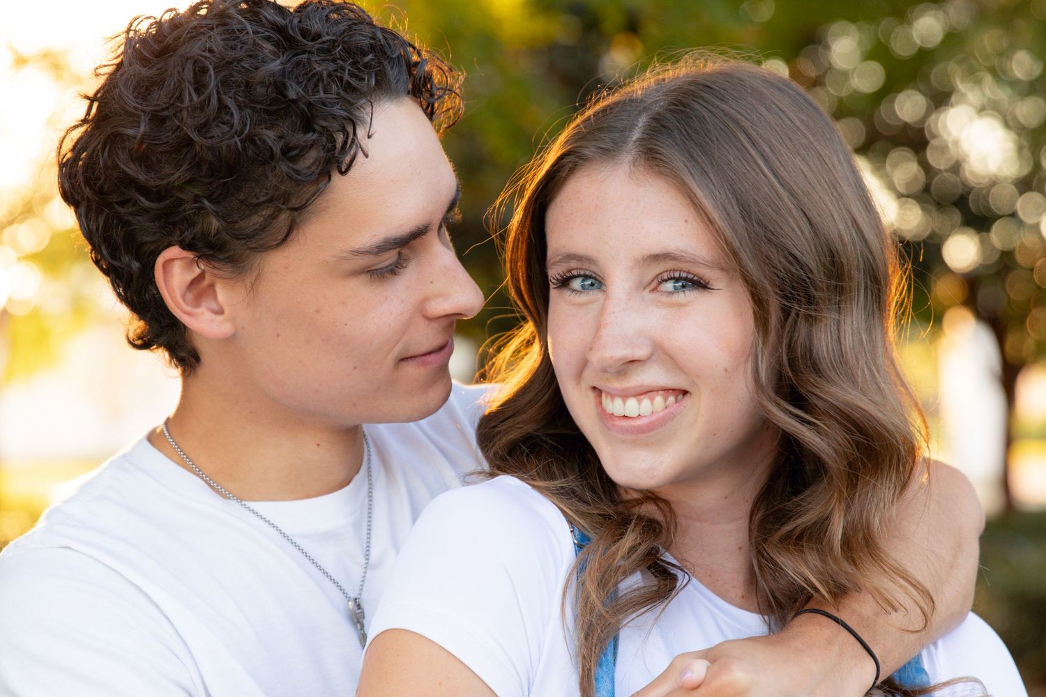 A couple shares tender moments during a golden hour outdoor photoshoot in a natural setting.