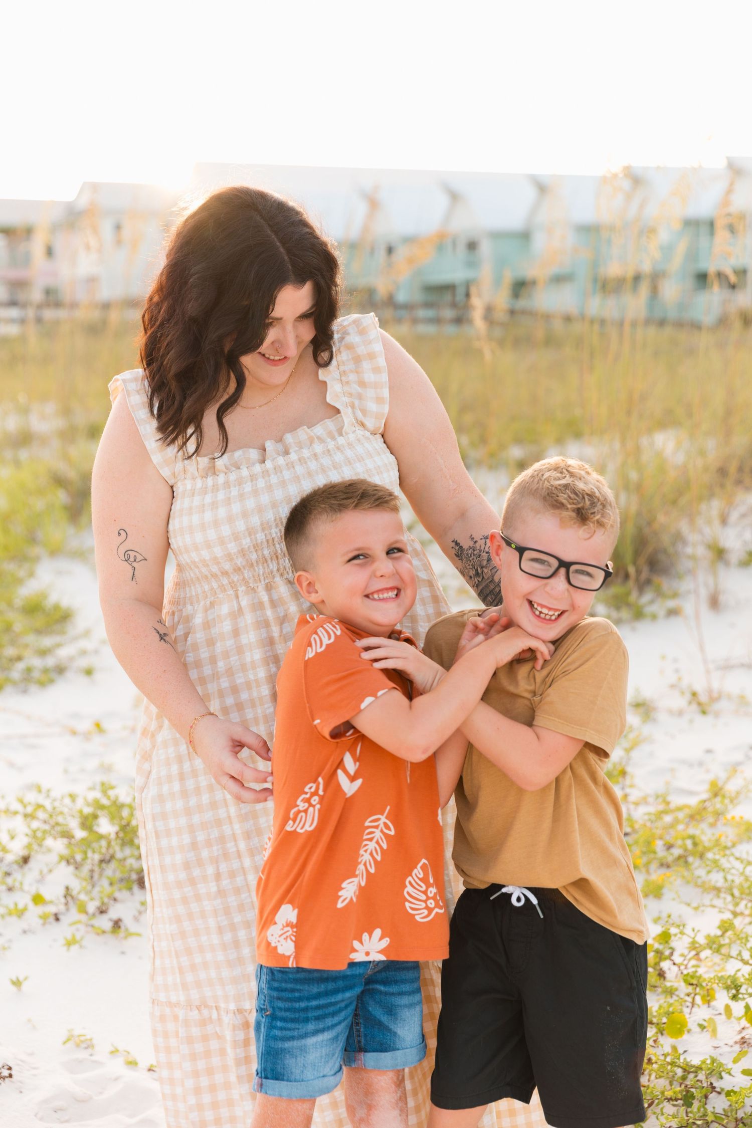 Family portrait with mother and two children playing together on a beach.