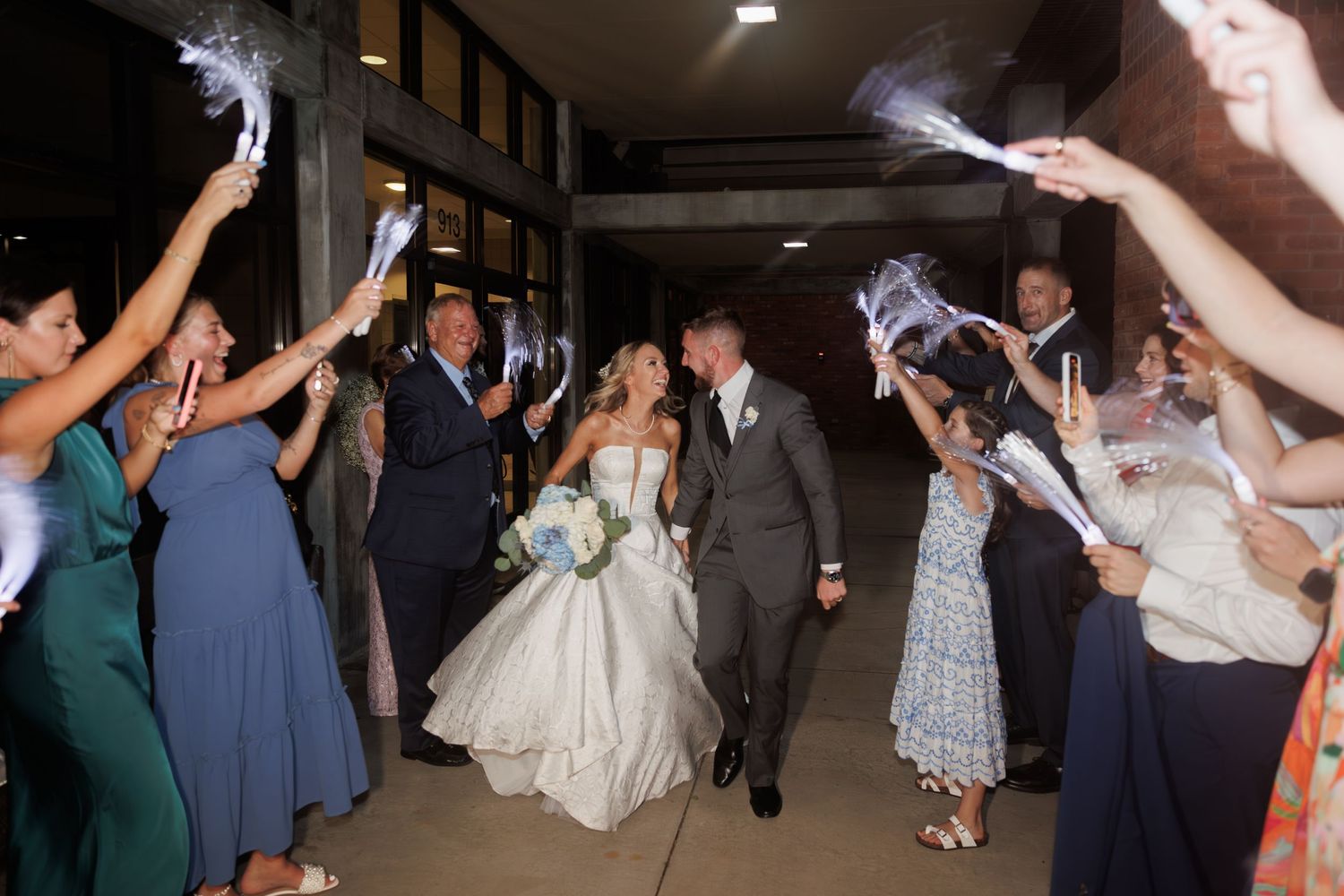Wedding couple makes grand exit through sparkler send-off with guests in formal attire lining the pathway.