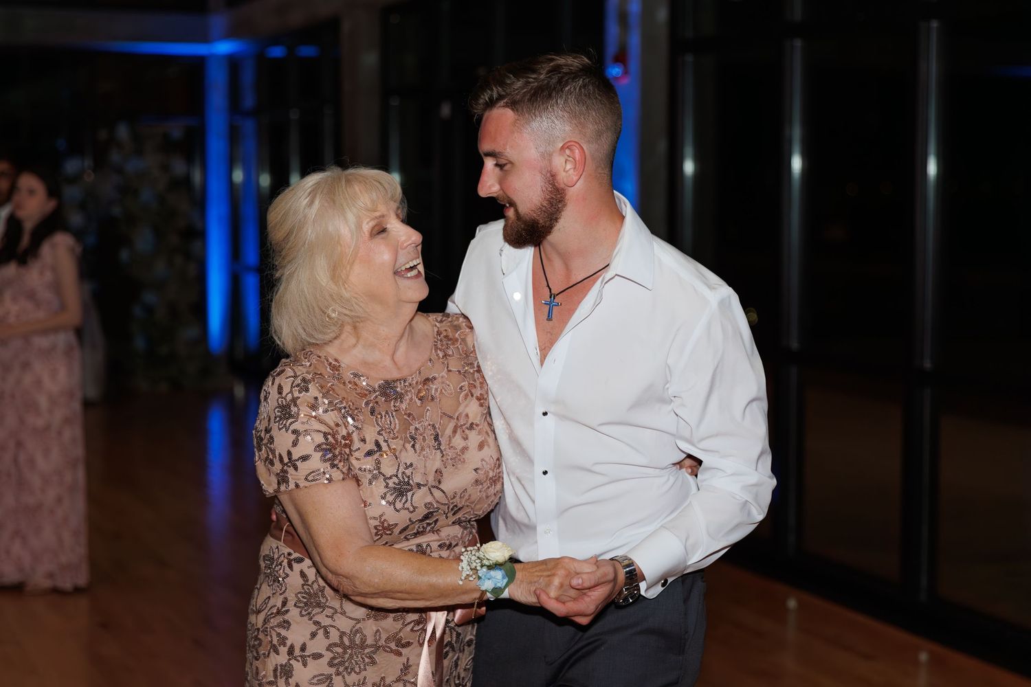A couple shares an intimate dance moment under blue lighting at a wedding reception.
