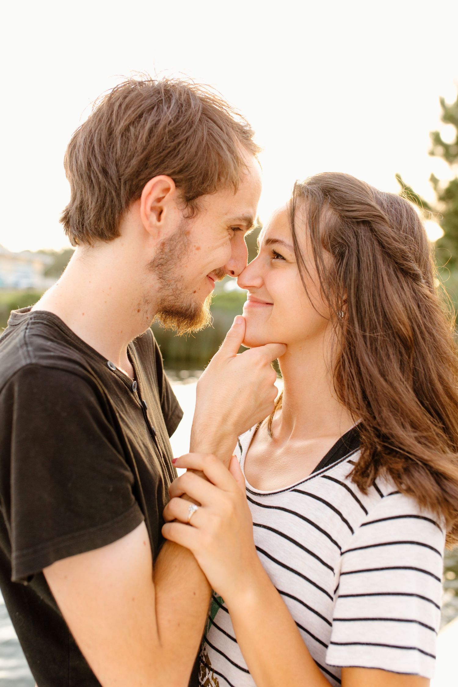 Couple in casual outfits sharing intimate close-up moment outdoors.