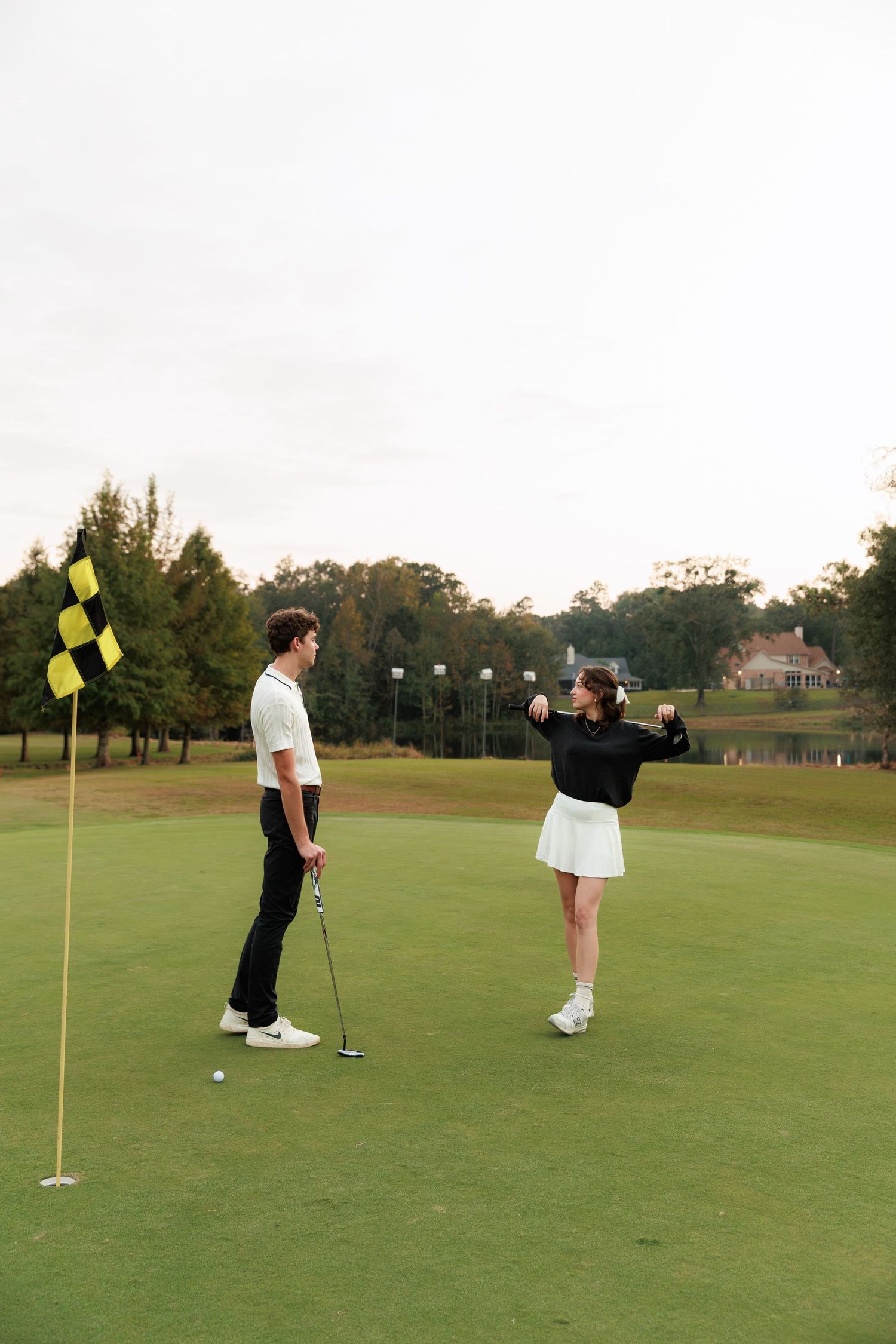 Golfers practicing their putting skills on a lush green golf course with yellow flag markers.