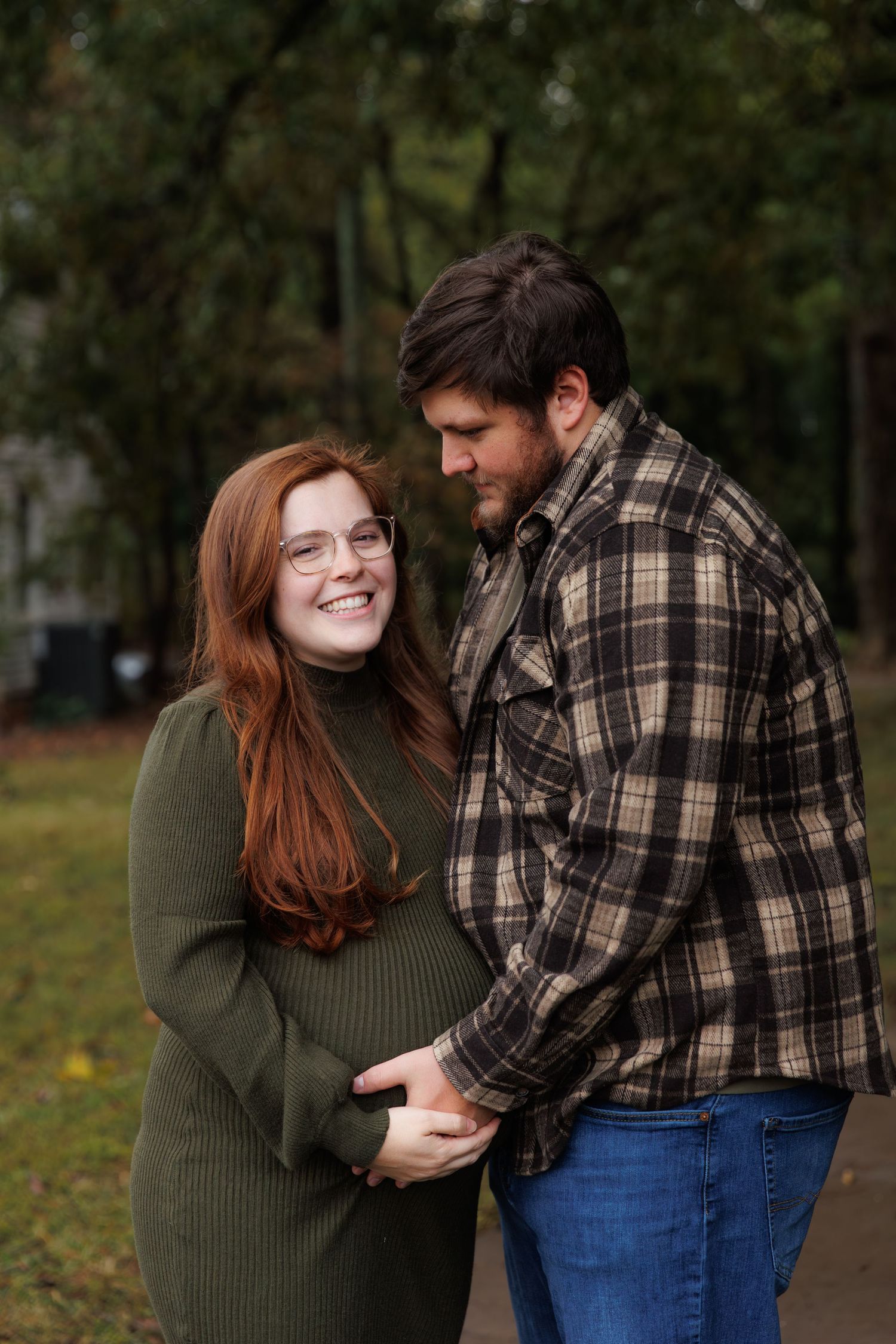 A couple in casual fall attire sharing sweet candid moments together in a park setting during autumn.