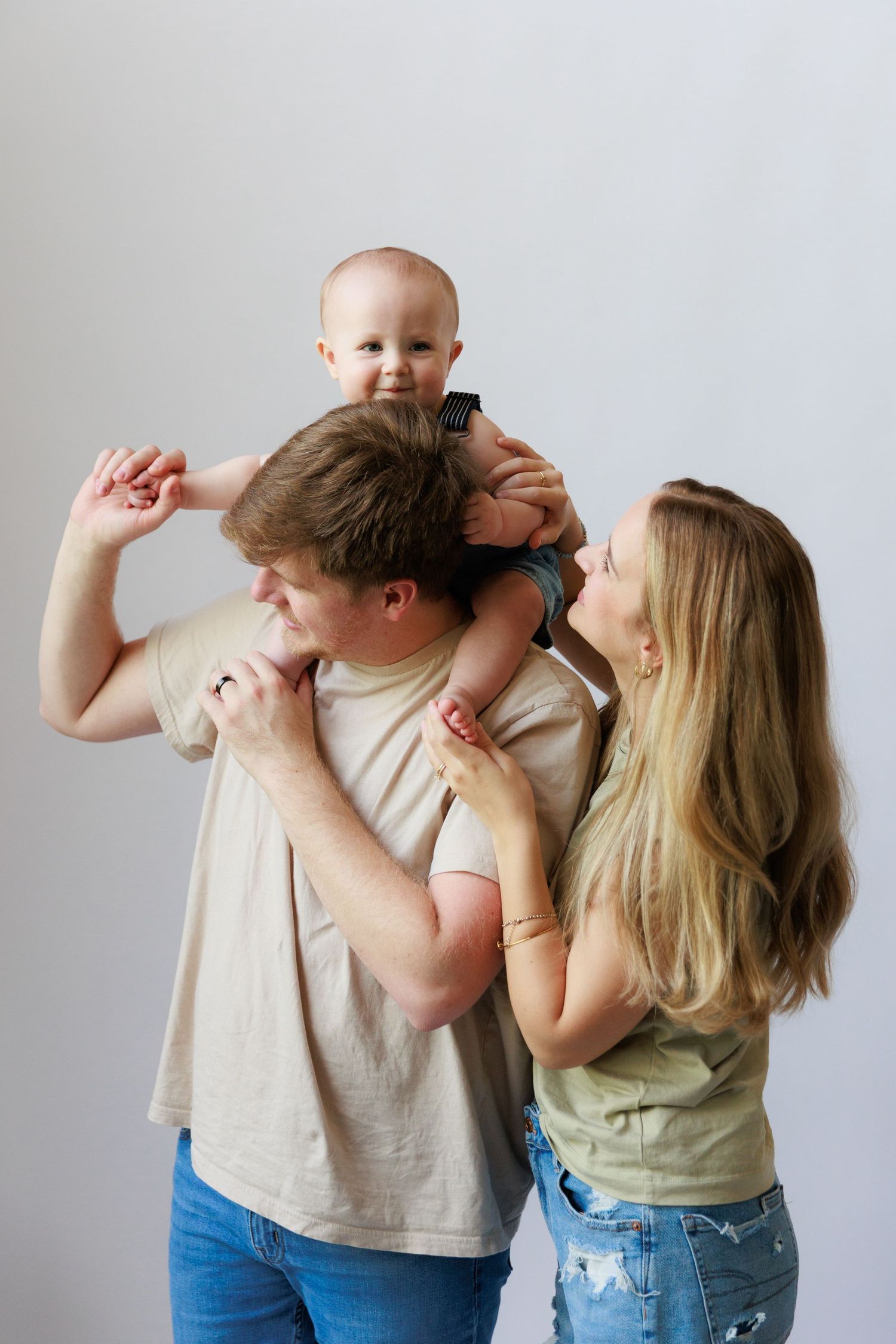 Playful family moment captured in casual clothing against white background.
