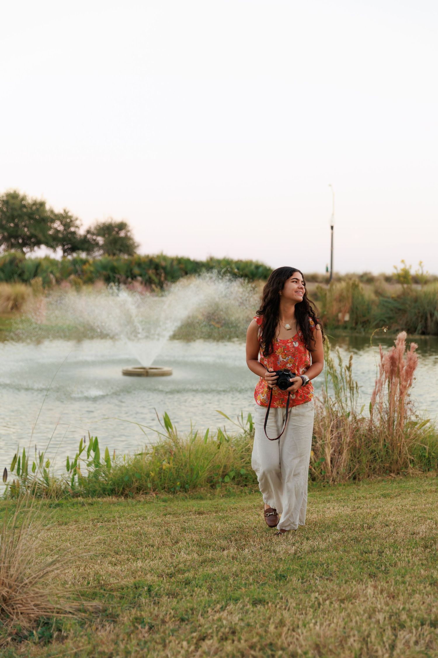 Photographer explores lakeside area with camera while fountain sprays in background.