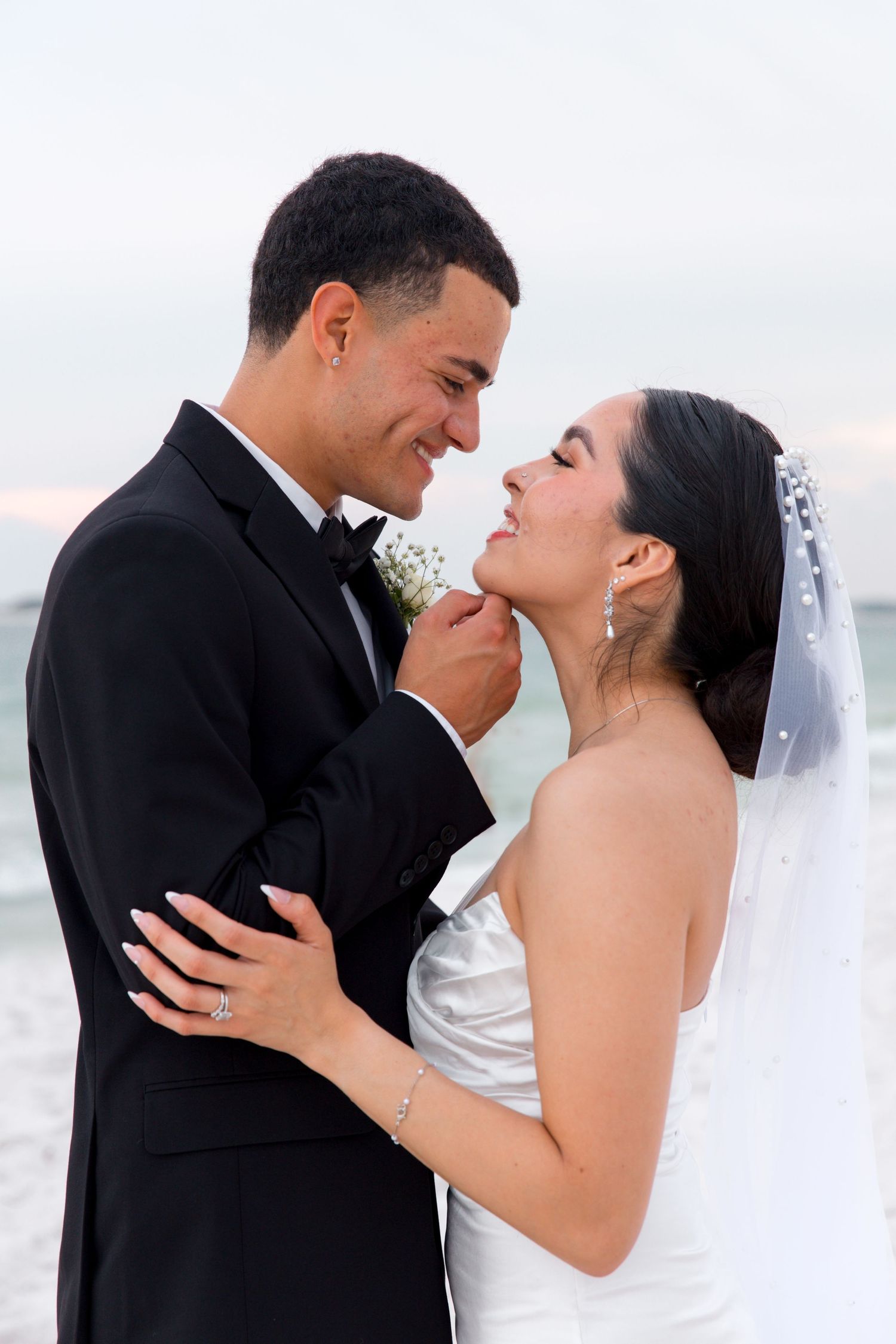 Joyful couple sharing loving moment during beach wedding photoshoot.