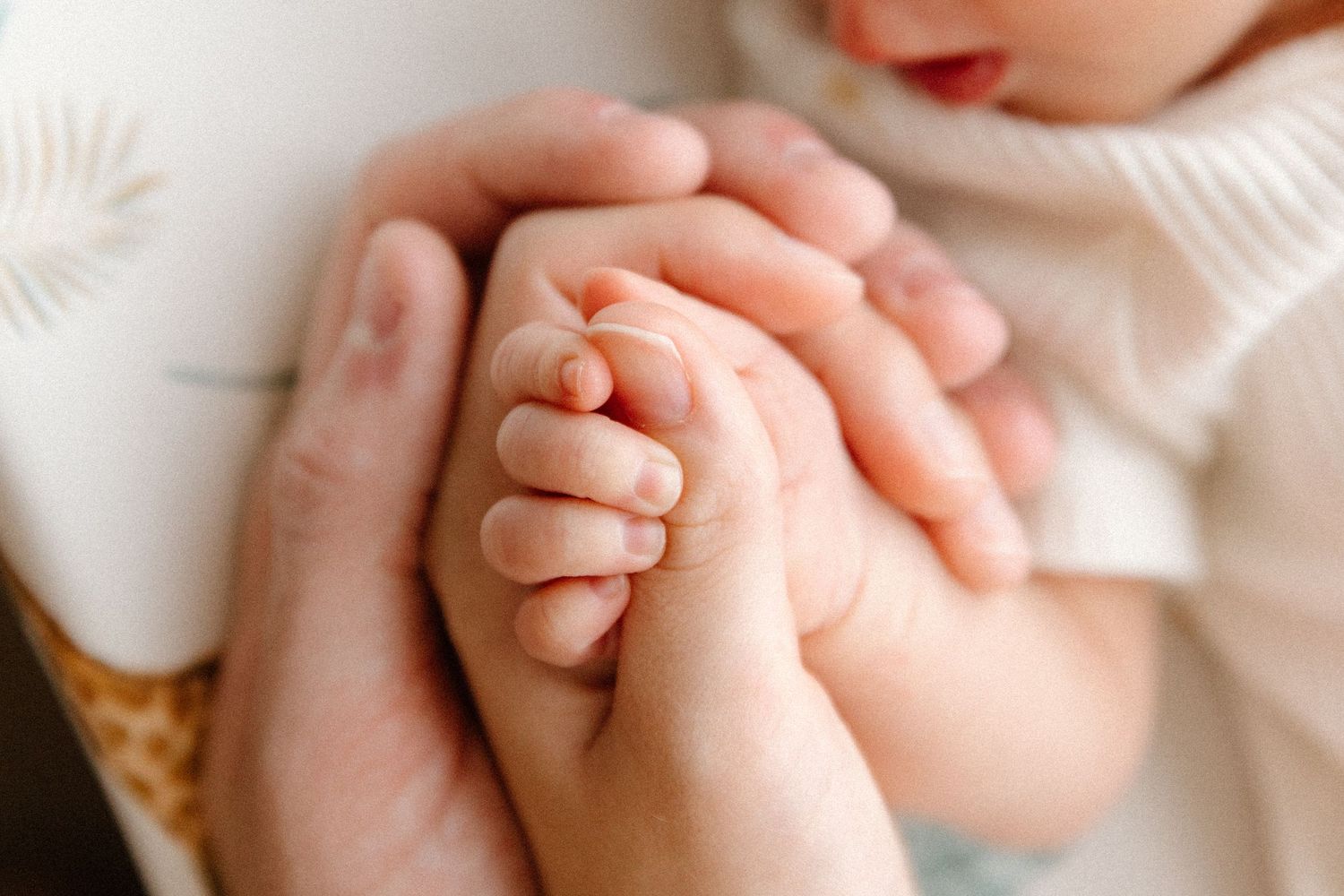 Close-up details of tiny baby fingers and hands against a soft white background.