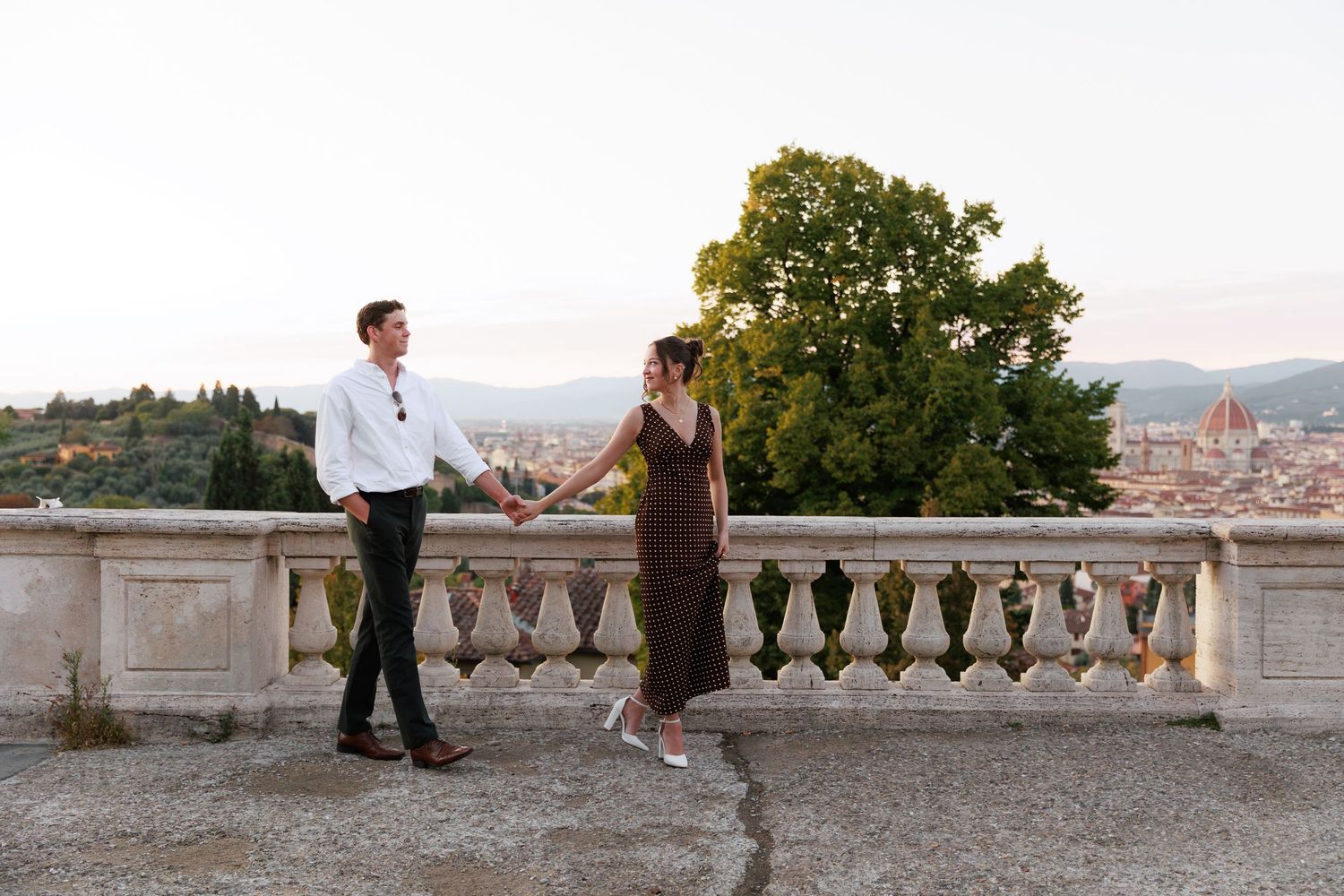 Couple walking hand in hand on a balcony with Florence cathedral in background.