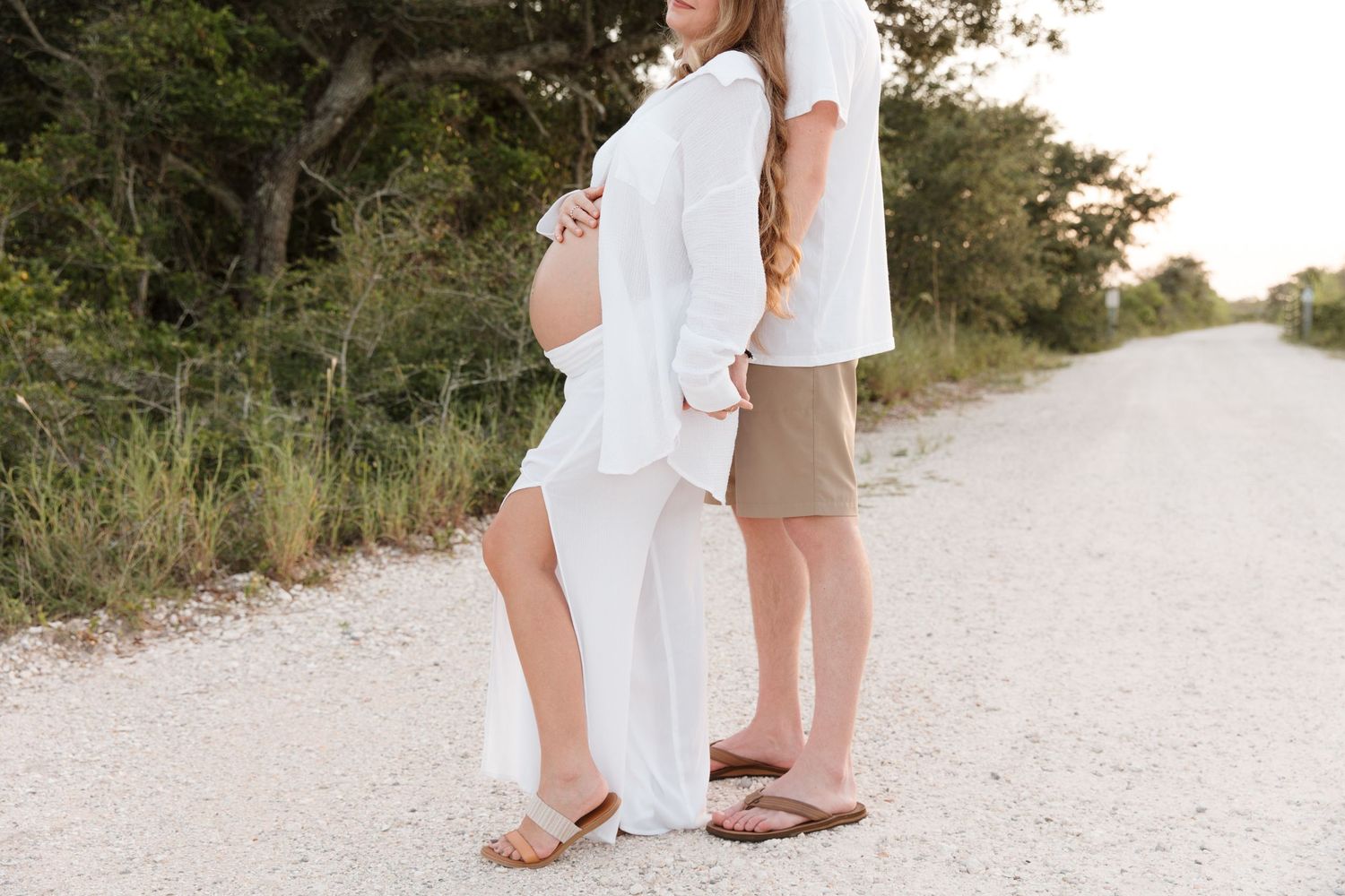 A romantic moment captured on a winding sandy path with lush greenery in the background.