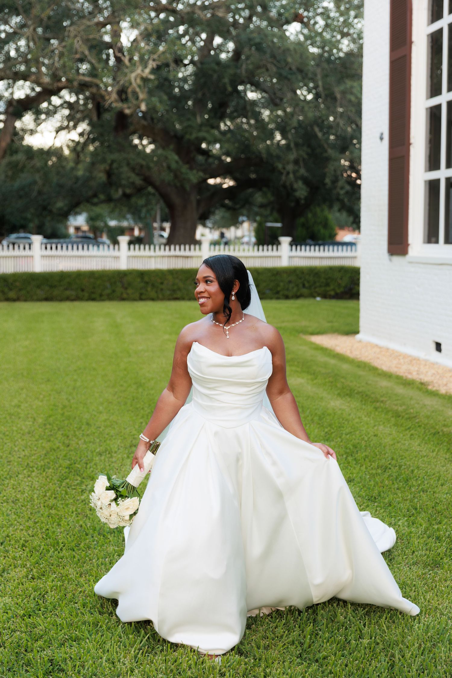 A joyful bride twirls in her flowing white gown on a manicured lawn.
