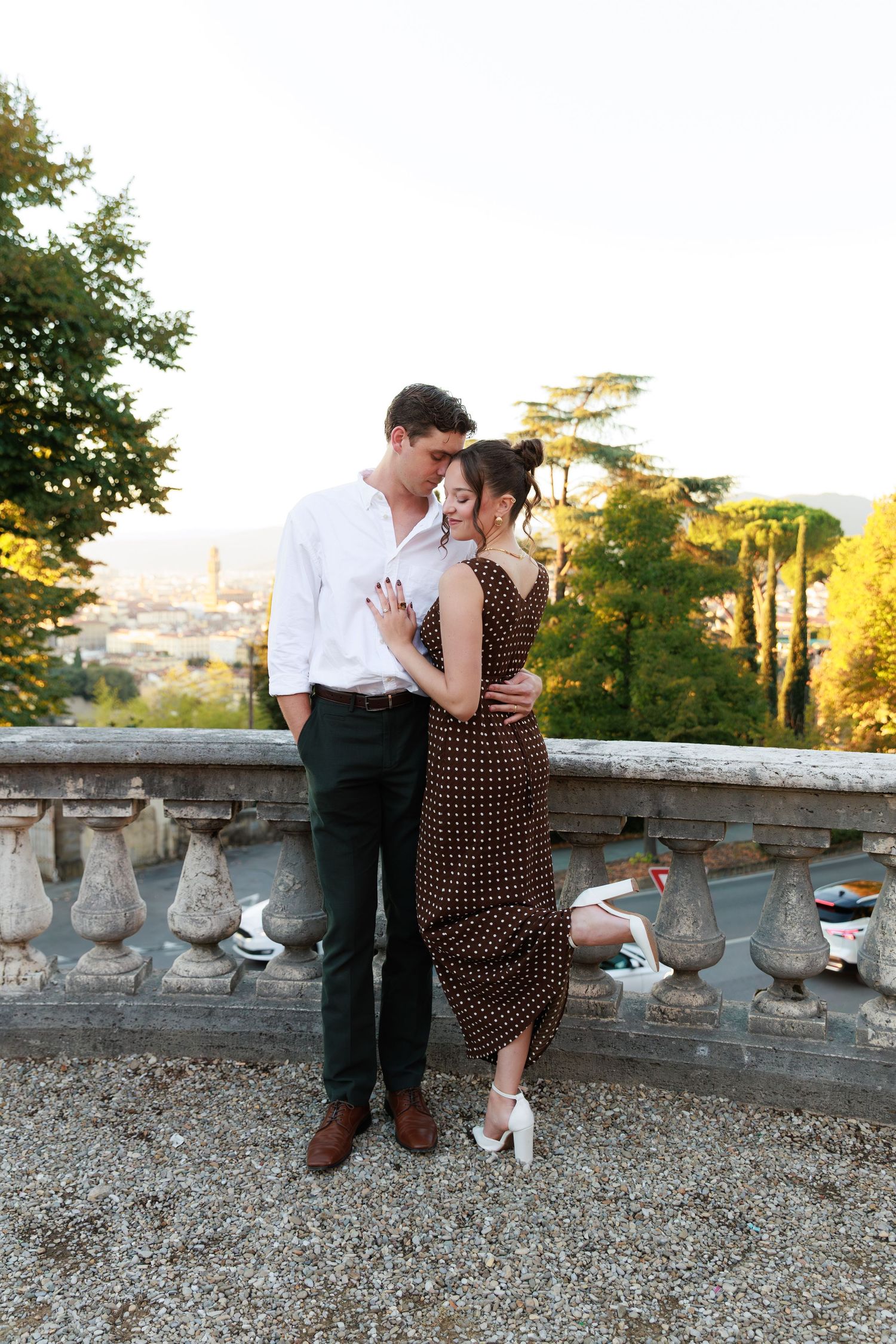 Romantic couple embracing on a stone terrace overlooking Florence, Italy at golden hour.