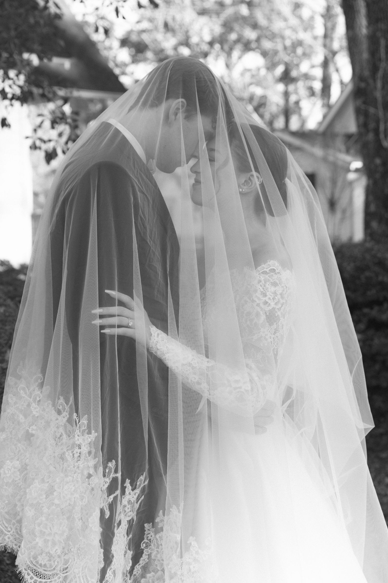 Close-up details of a delicate white bridal veil with intricate lace patterns.