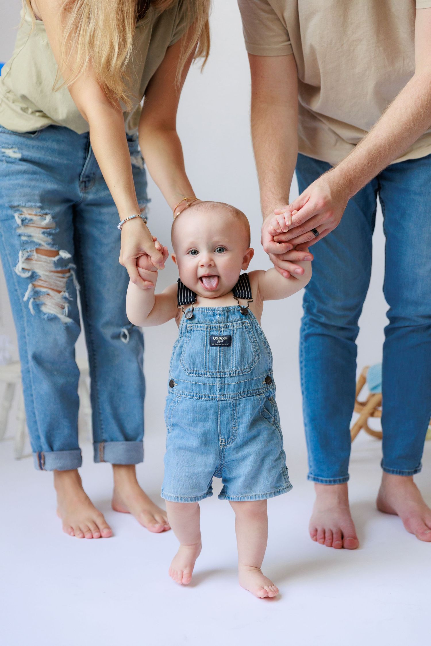Family feet and legs lined up against white wall showing jeans and denim overalls.