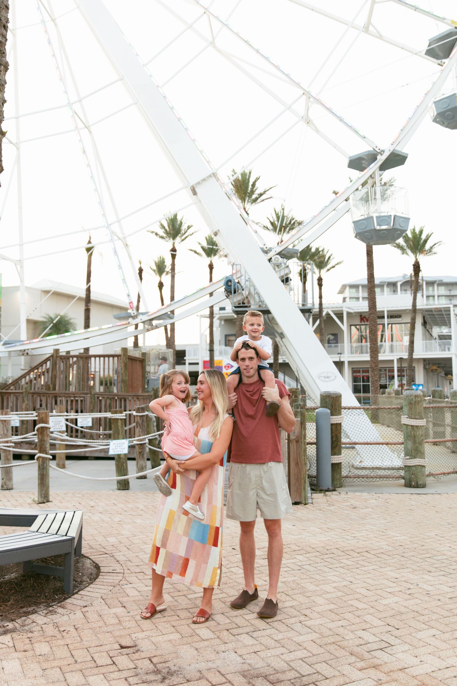 Family walking together under a white canopy structure near palm trees at dusk.