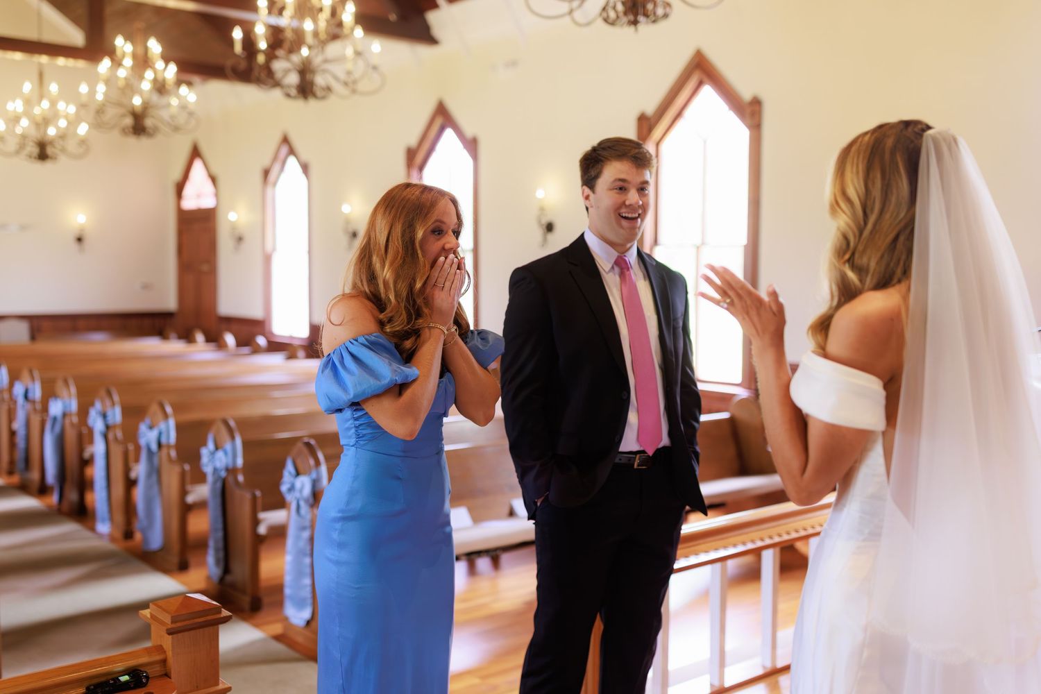 People having a conversation inside a traditional church chapel with wooden pews and gothic arched windows.