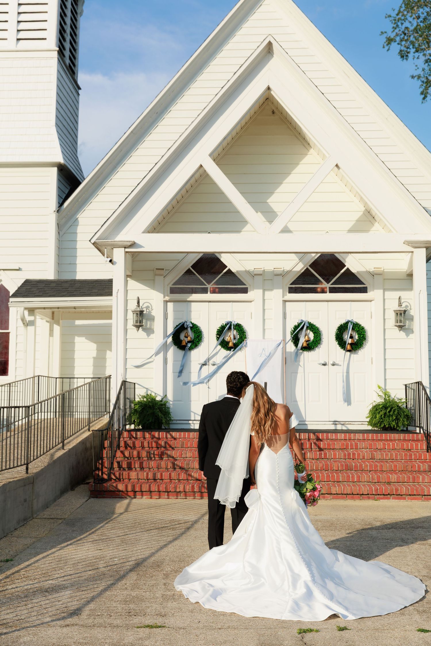 White church exterior with brick steps and green holiday wreaths showing different wedding photography angles.