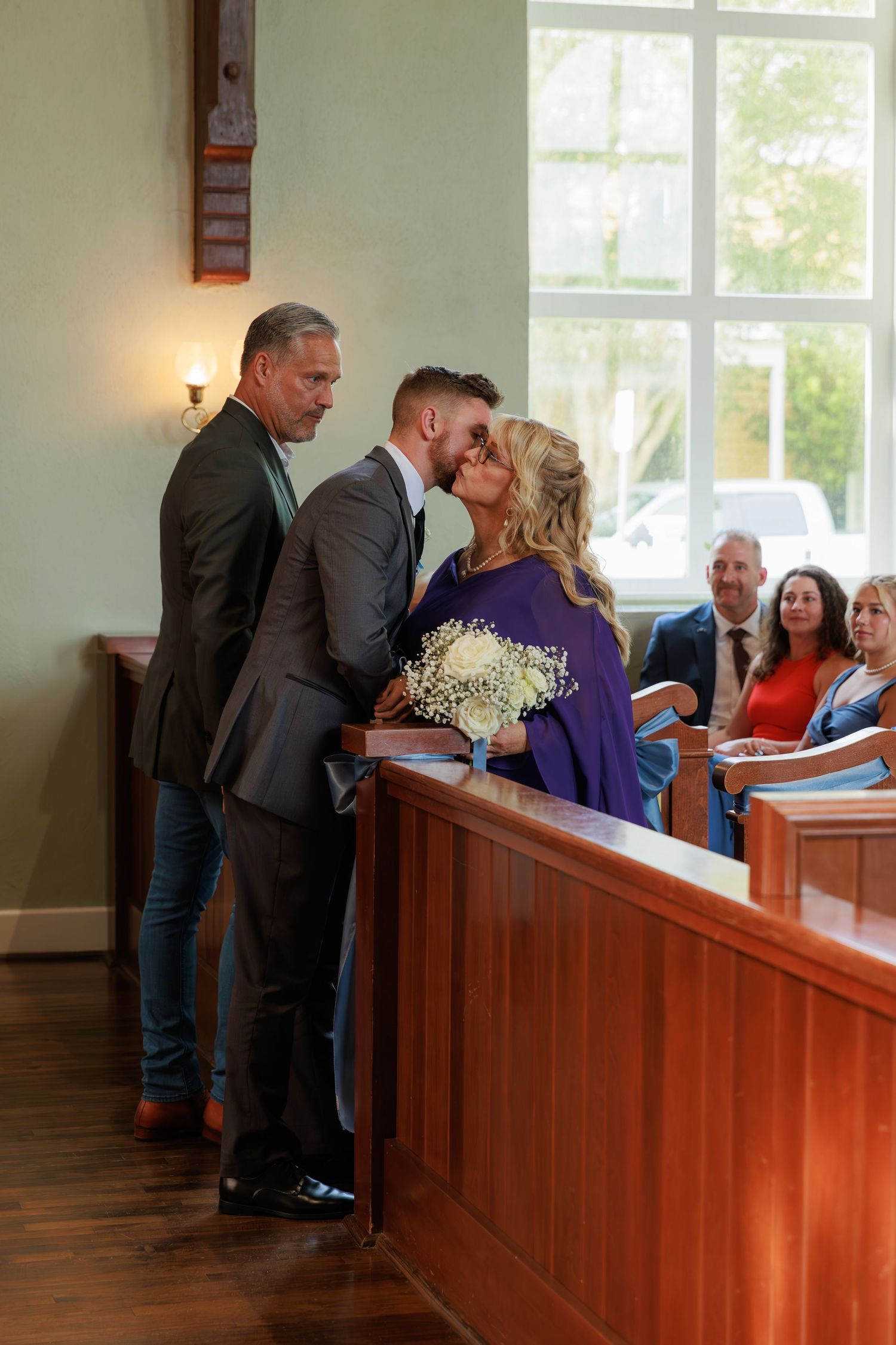 Wedding attendants interact joyfully during a church ceremony.