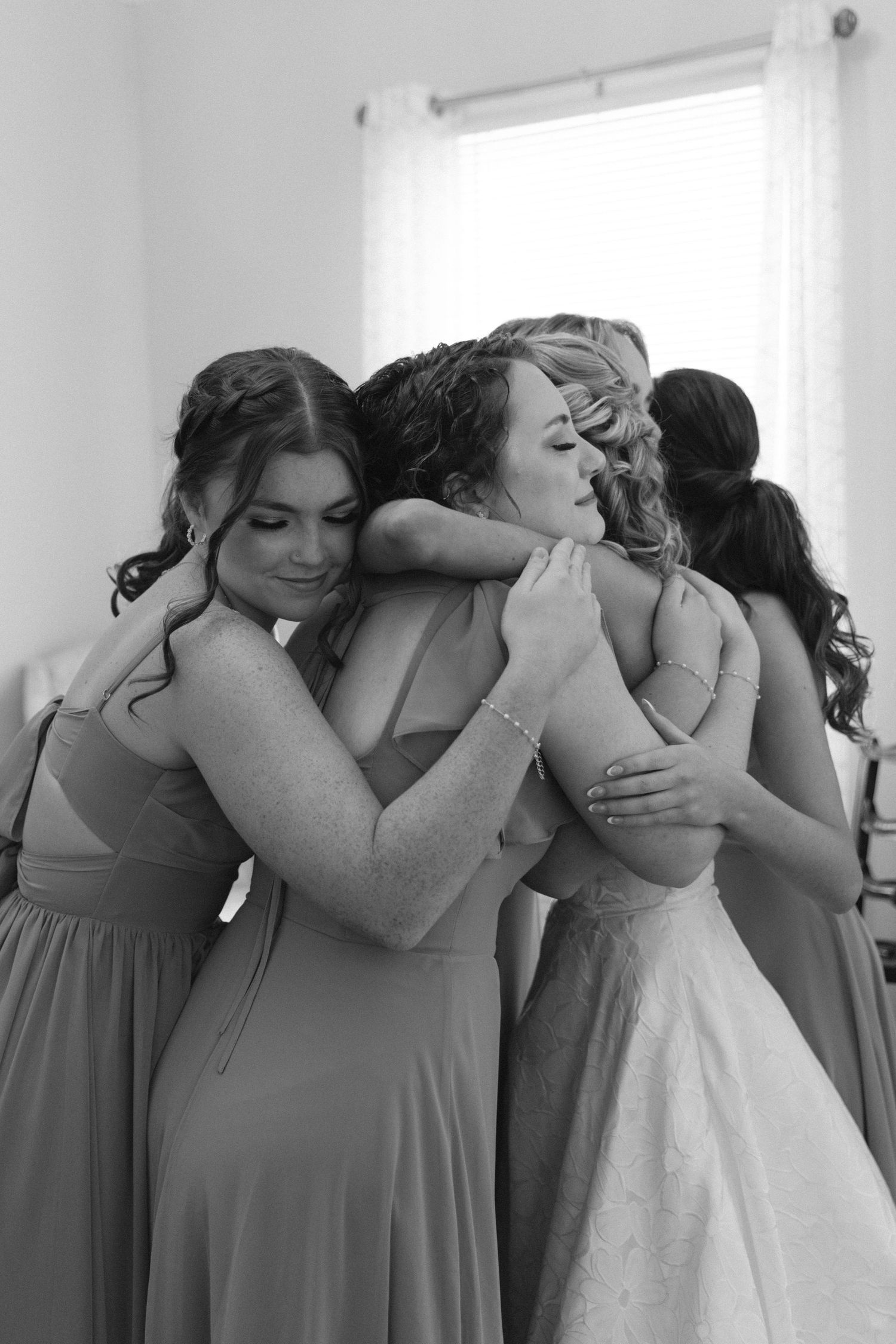 An emotional group embrace showing formal dresses in black and white.