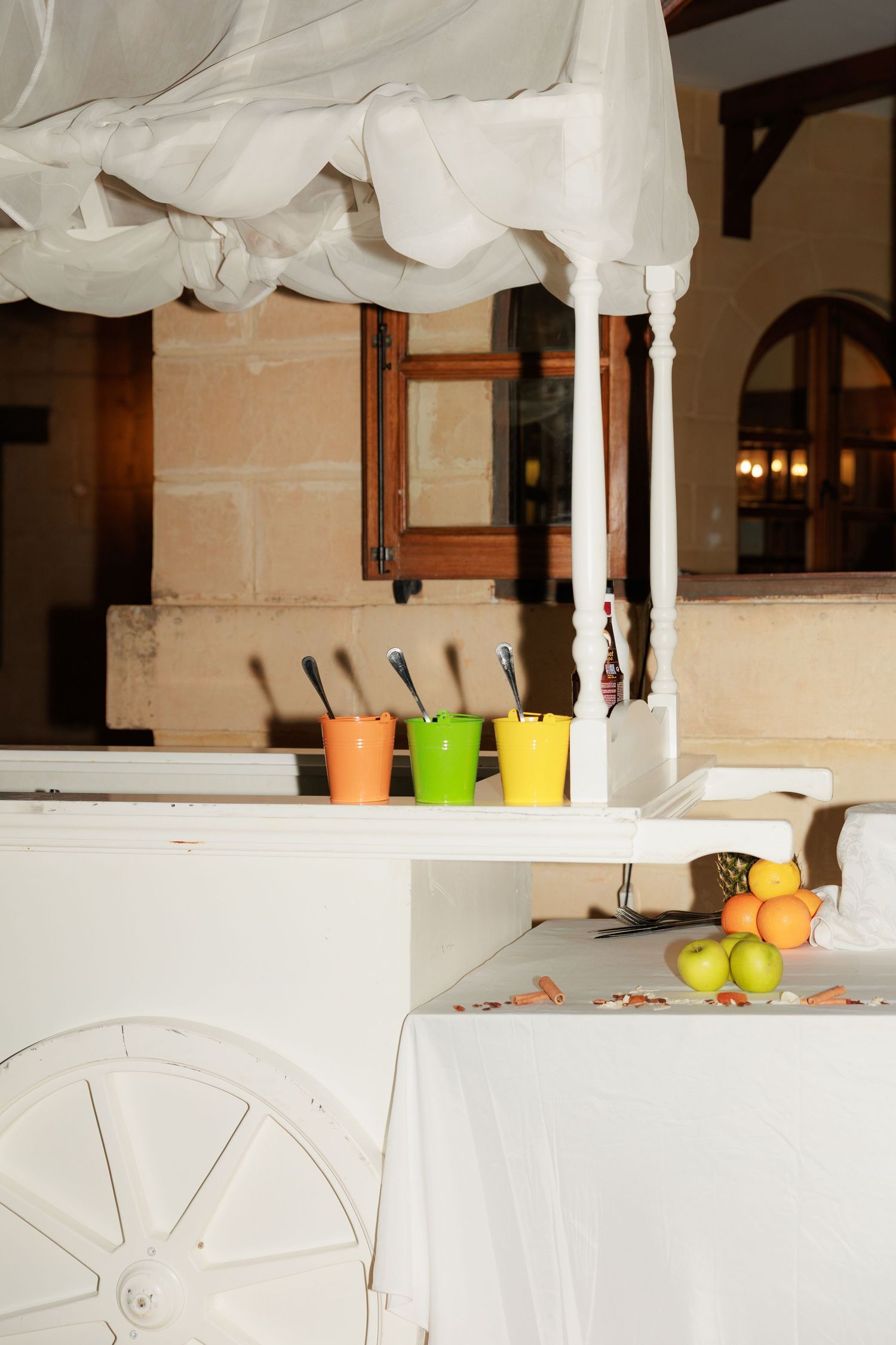 White fabric draped from ceiling with hanging decorative elements and colorful accents in an indoor venue.