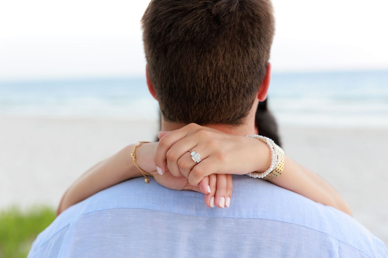 Romantic couple embraces on a sunny beach during a destination wedding celebration.