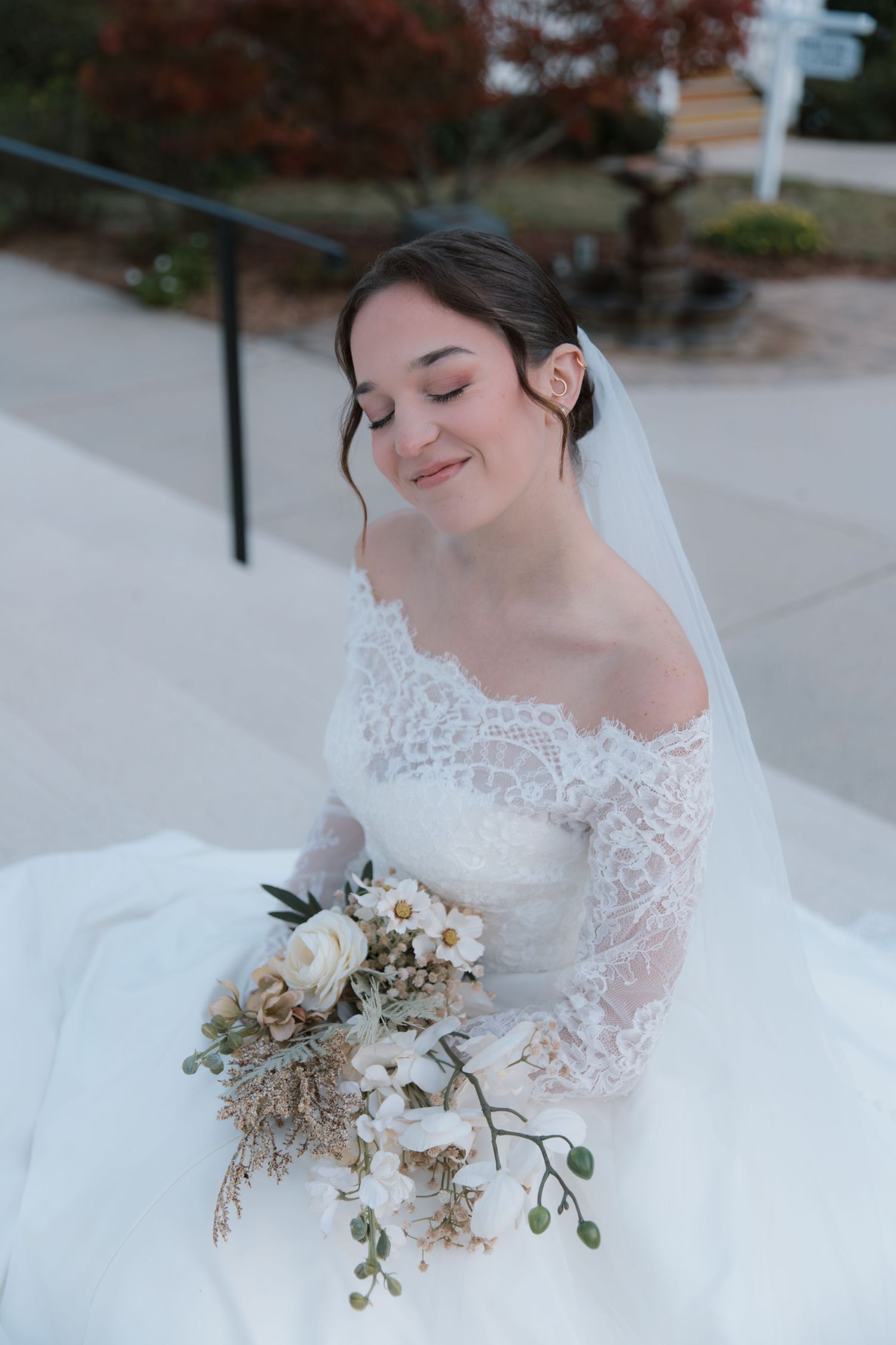 A delicate bridal bouquet of dried flowers and greenery complements a classic lace wedding gown.