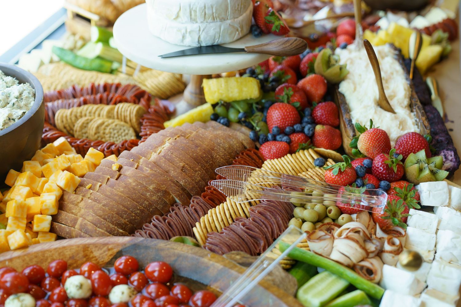 A colorful charcuterie board featuring meats, cheeses, fresh berries, crackers and assorted fruits arranged on a platter.