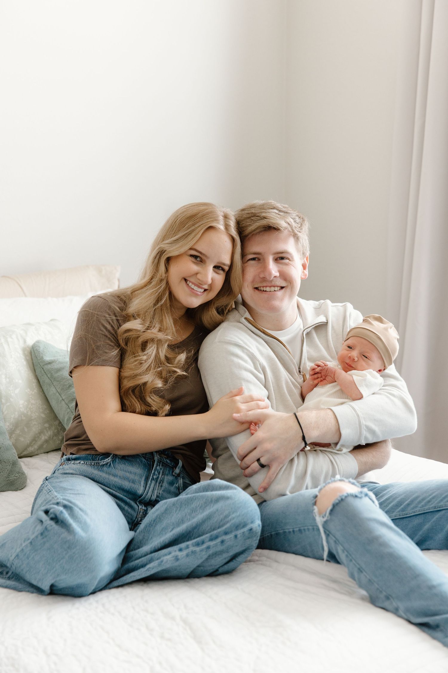 Family lying together on a bed with soft lighting in a cozy bedroom setting.