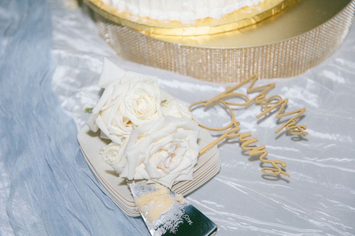 Wedding cake details with white roses and gold decorative elements.