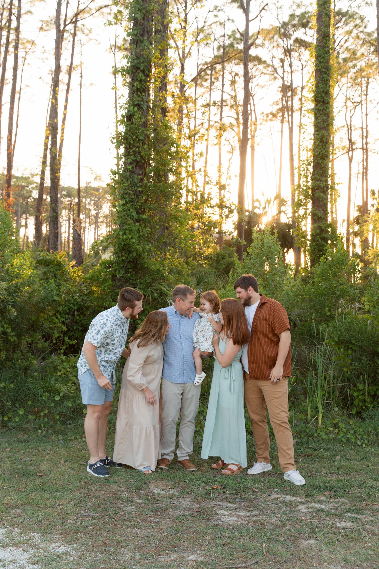 Group photo session in wooded area during golden sunset with pine trees in background.