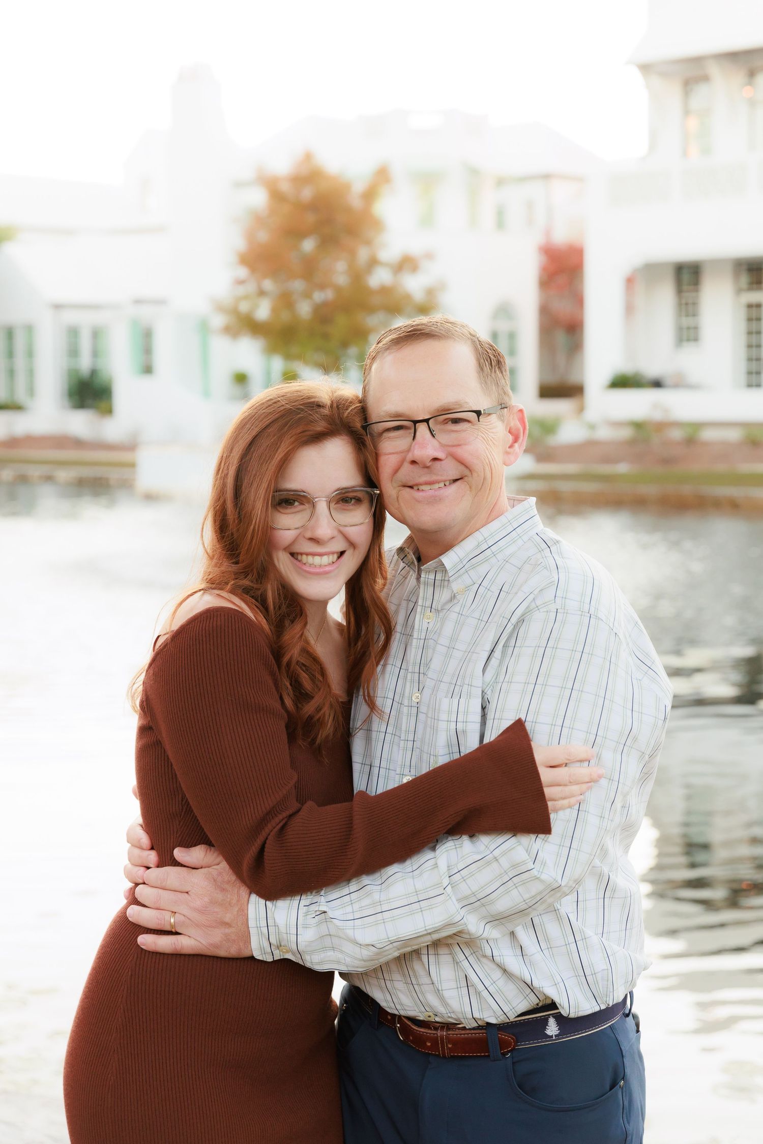 Sweet embrace captured during autumn outdoor portrait session near water.