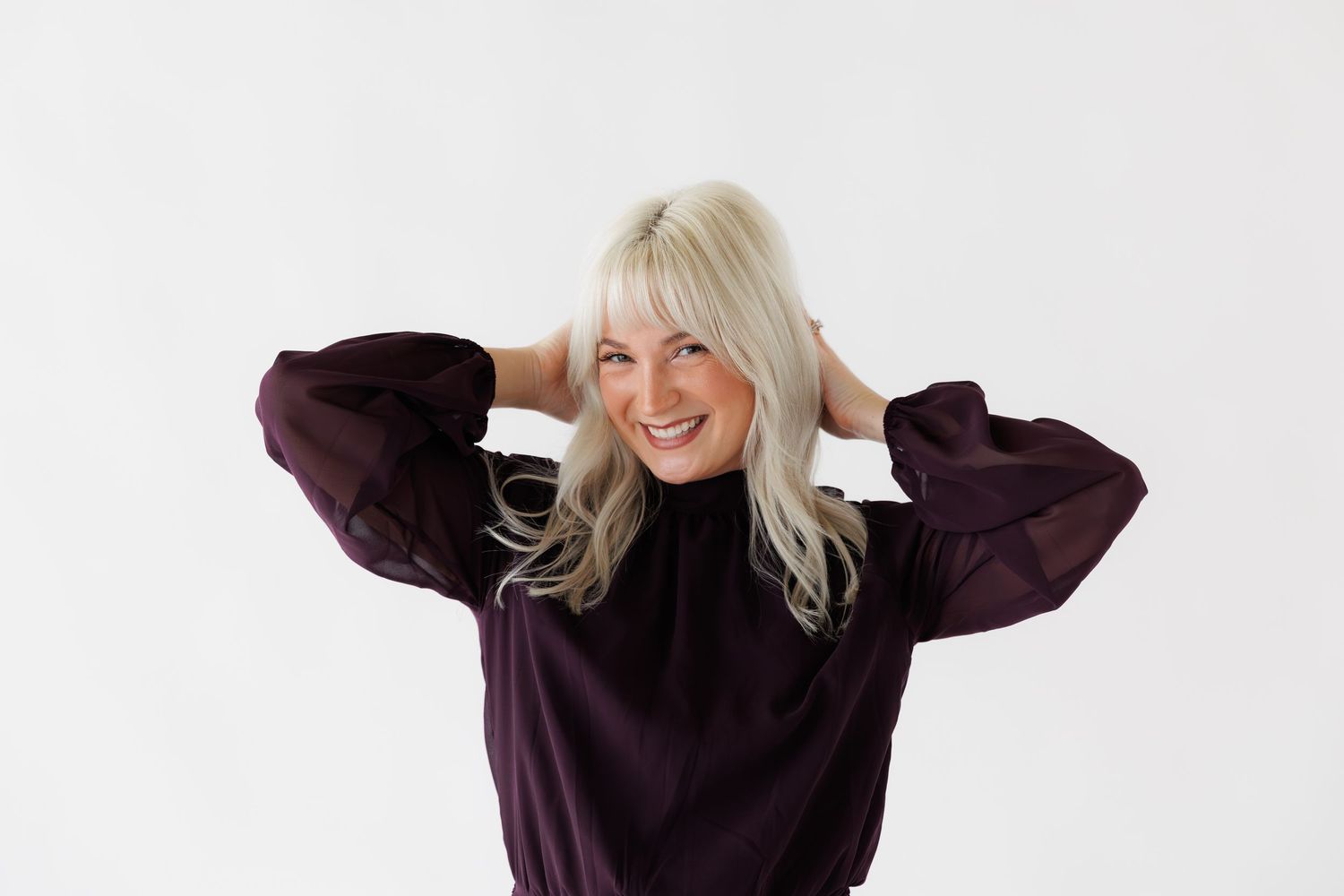 A person wearing a dark purple sweater poses playfully in a series of expressive shots against a light background.