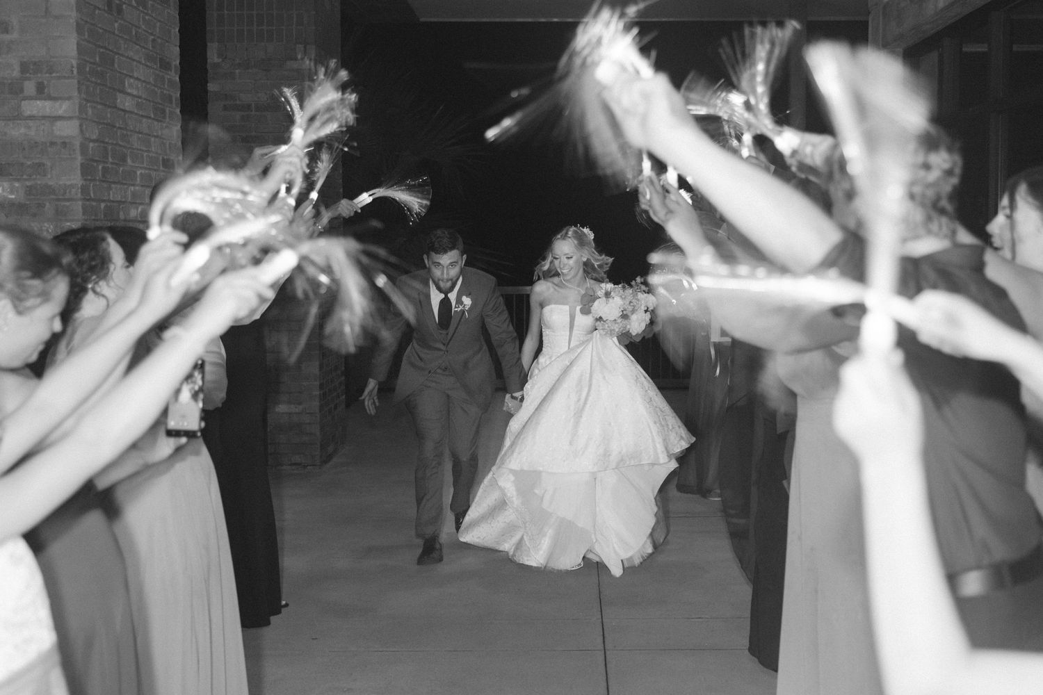 Black and white photo of bride and groom during sparkler exit celebration.