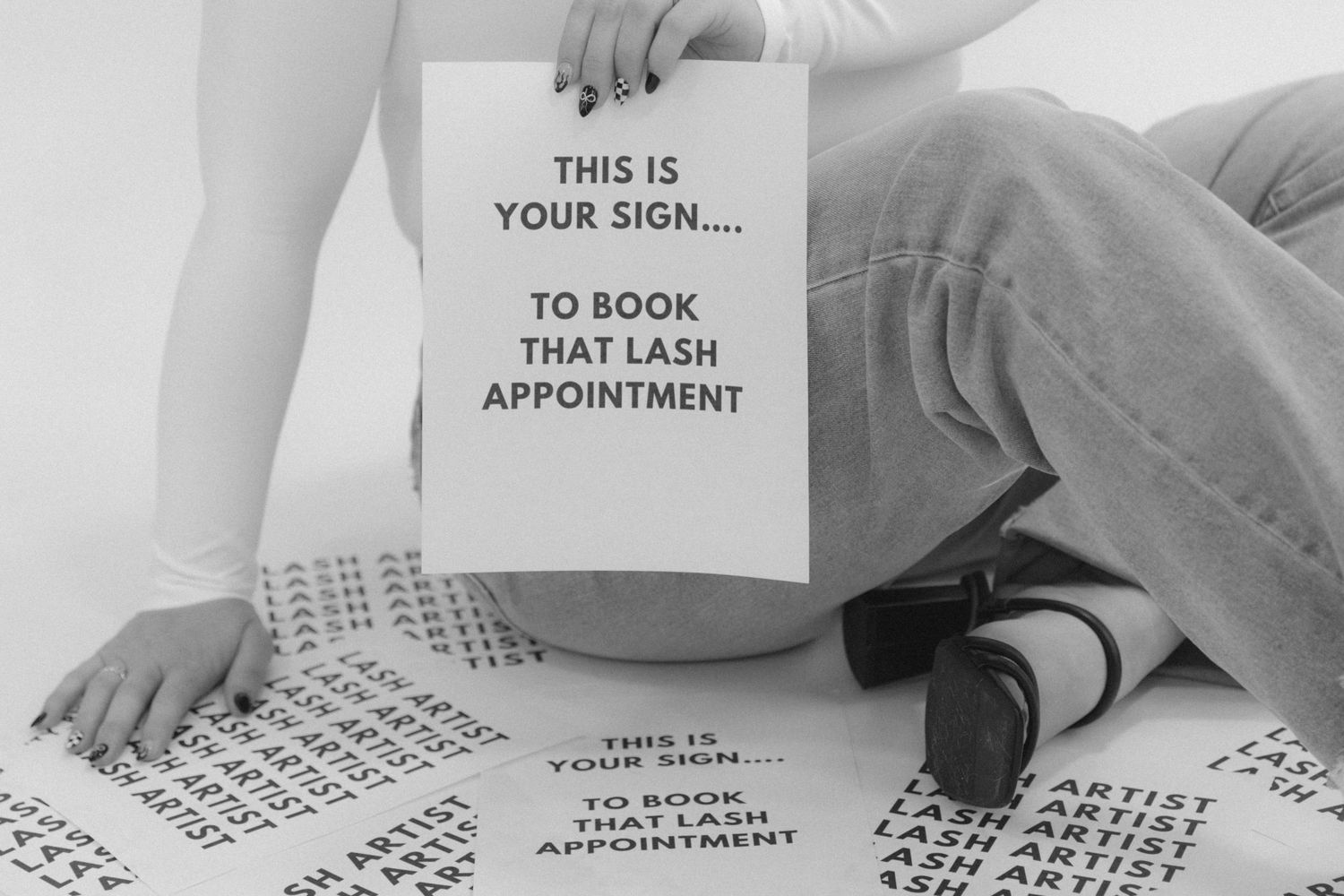 A black and white image showing a sign and appointment calendar sheets scattered on the floor.