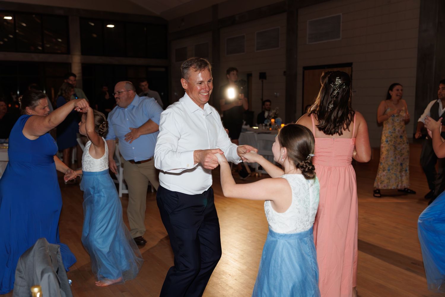 Guests dancing together at a wedding reception on a wooden dance floor.
