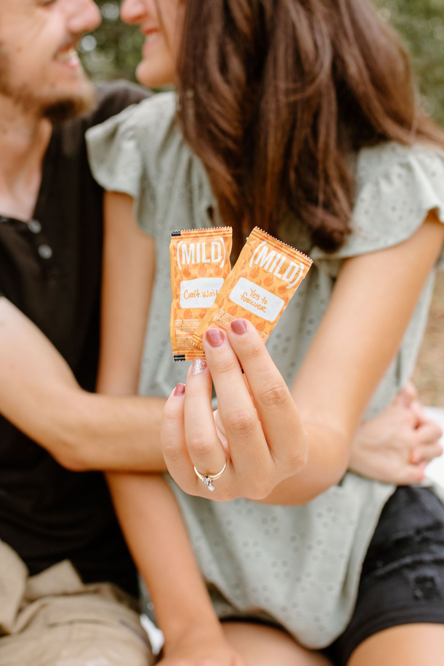 Close-up of hands holding orange snack packages during intimate moment.