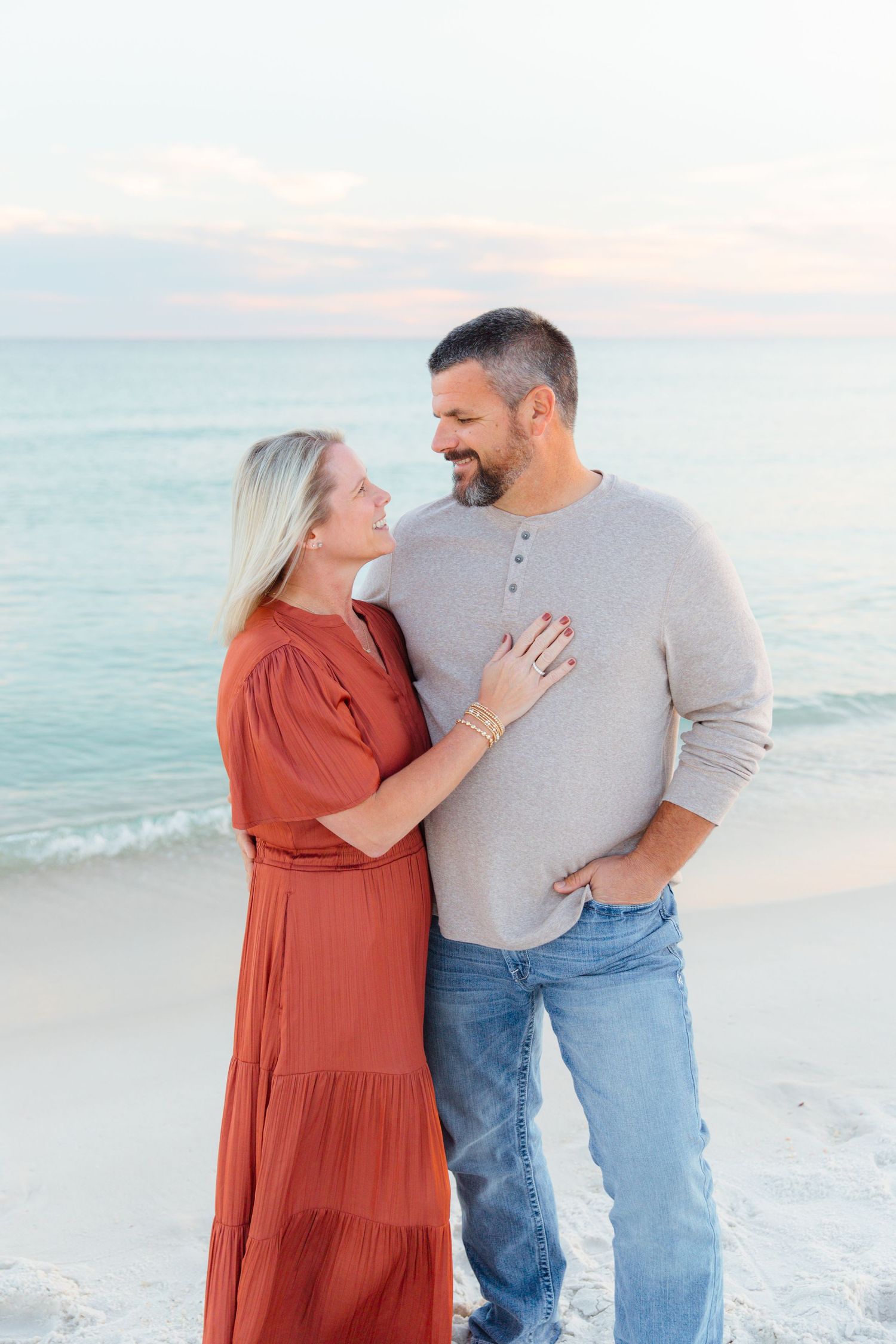Couple sharing intimate moment while standing on beach at sunset.