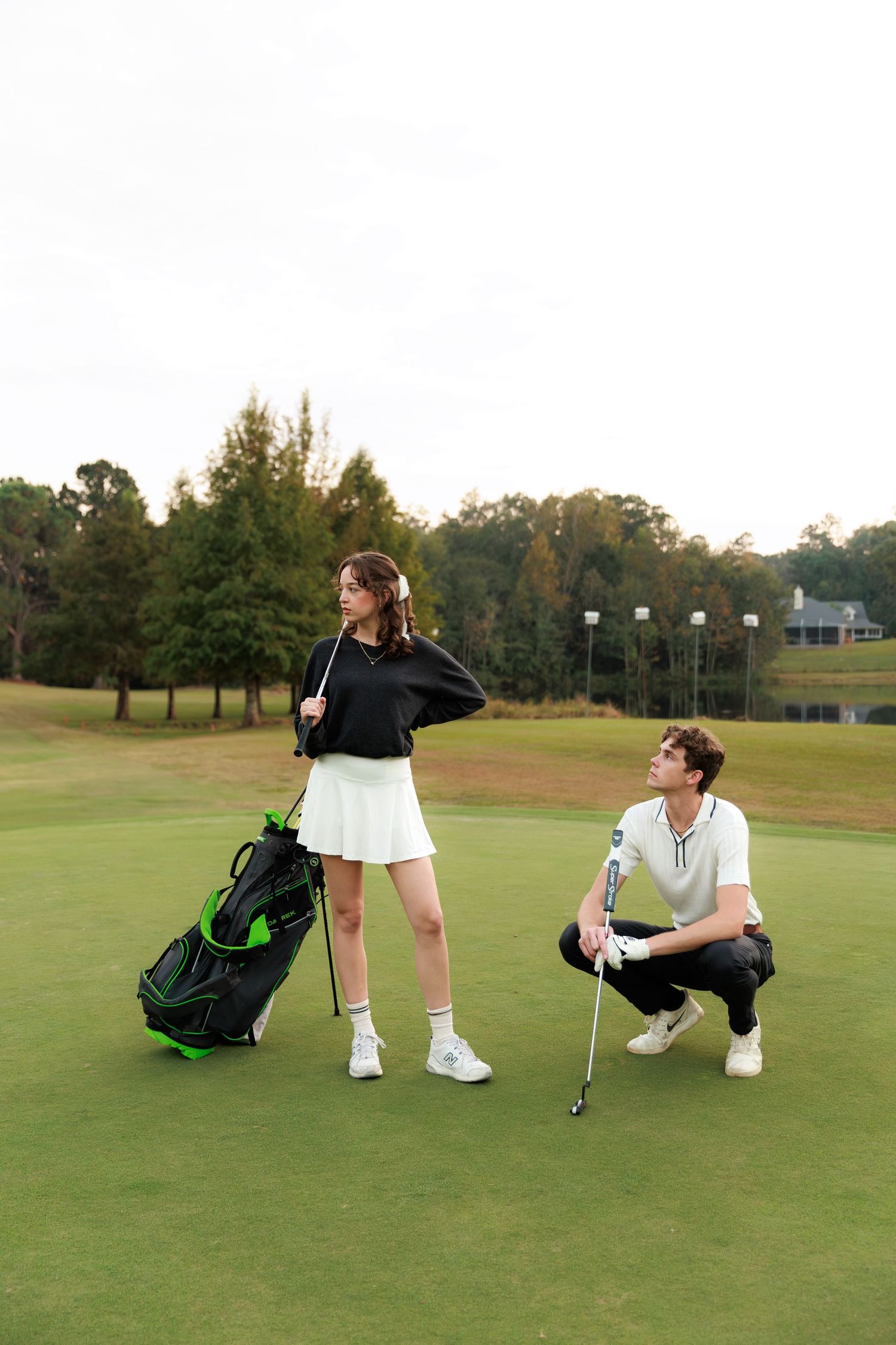 Two golfers relaxing and sitting on the green grass of a golf course next to their golf bags at sunset.