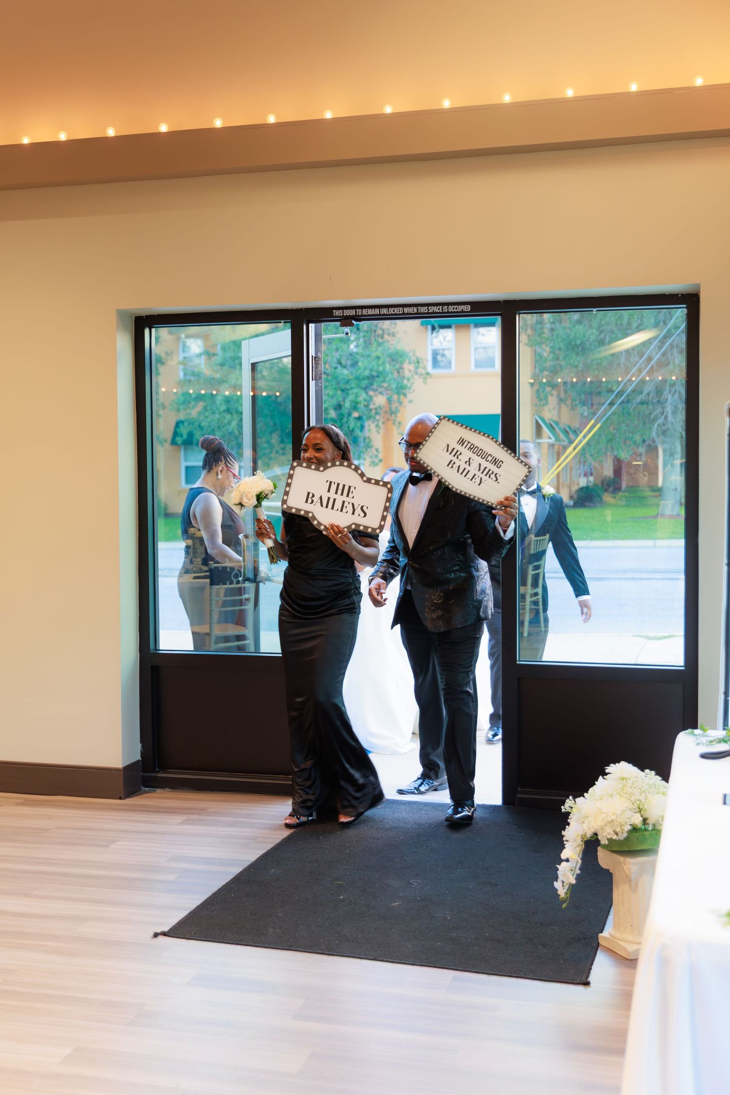 Wedding venue staff prepare the entrance area by rolling out a black carpet runner for an upcoming ceremony.