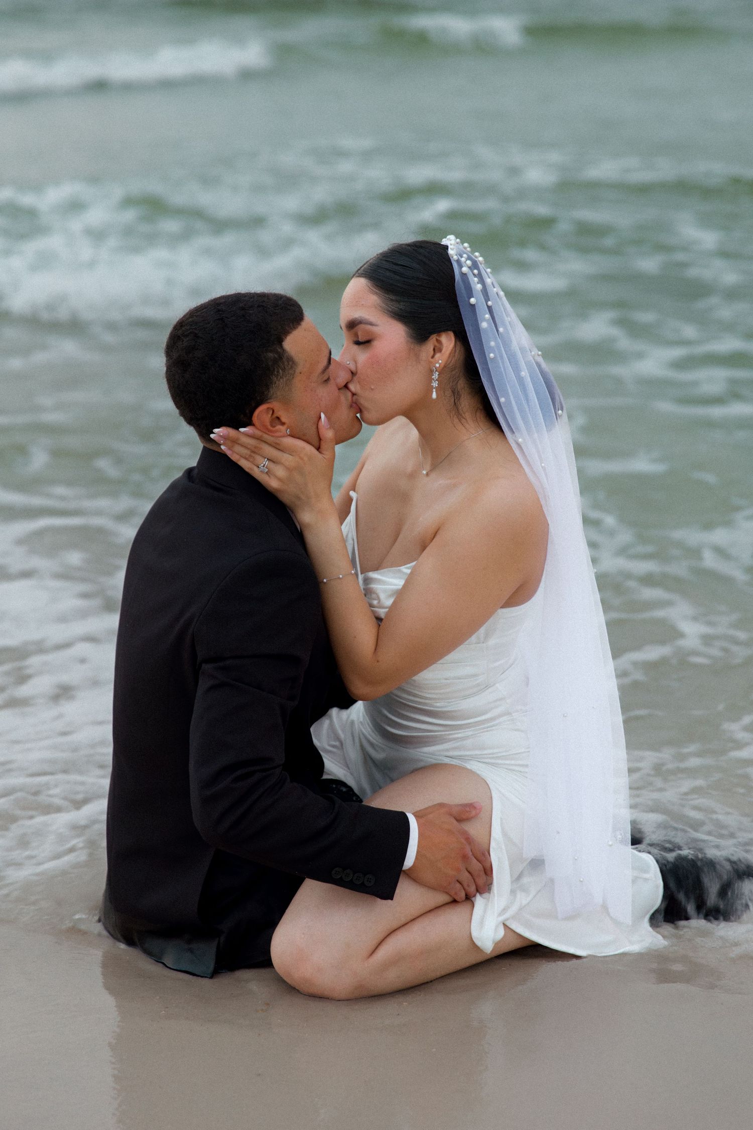A romantic beach wedding photo showing a couple sharing an intimate moment by the ocean.