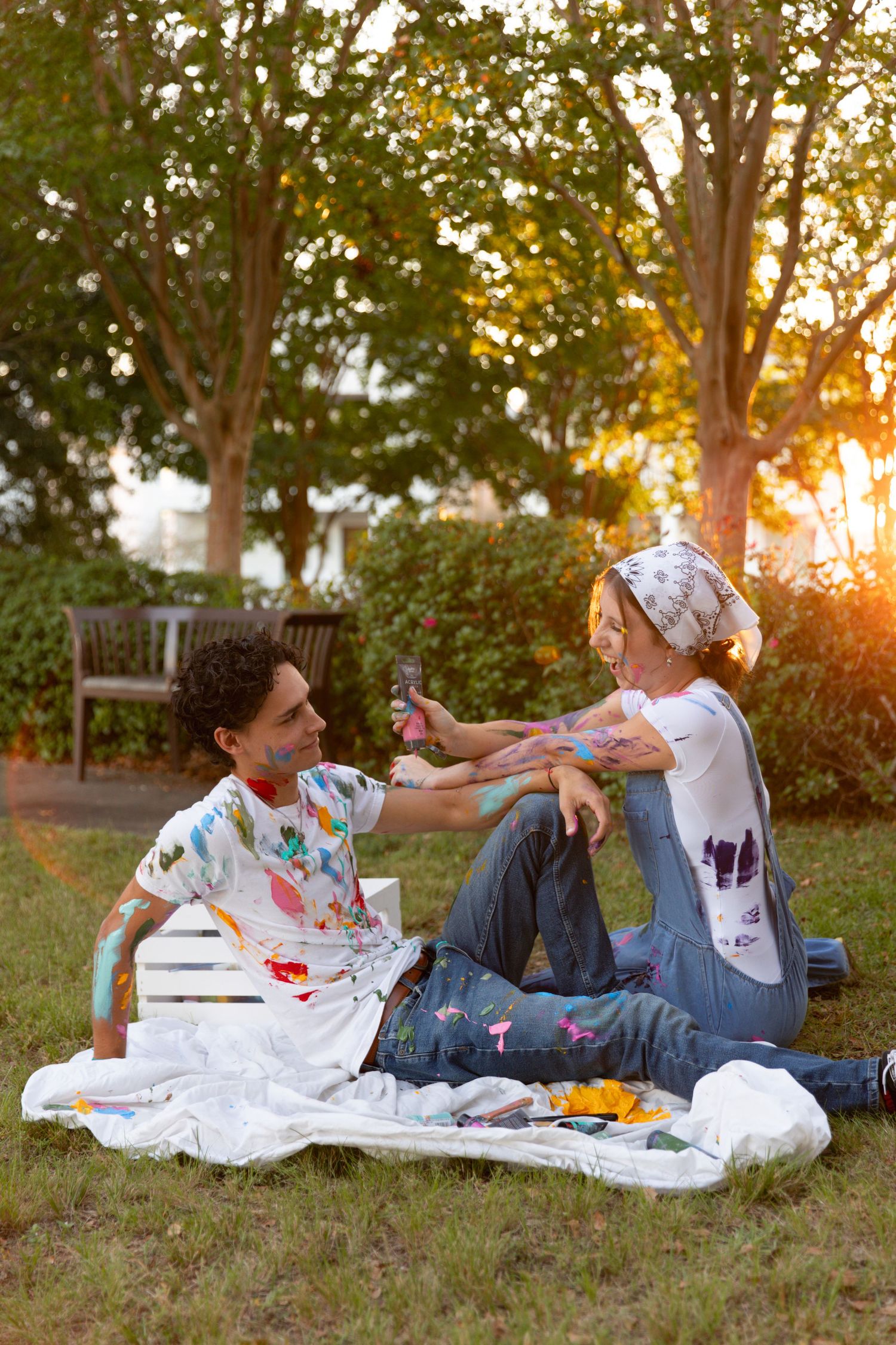 Couple in paint-splattered clothes having fun during outdoor photoshoot.
