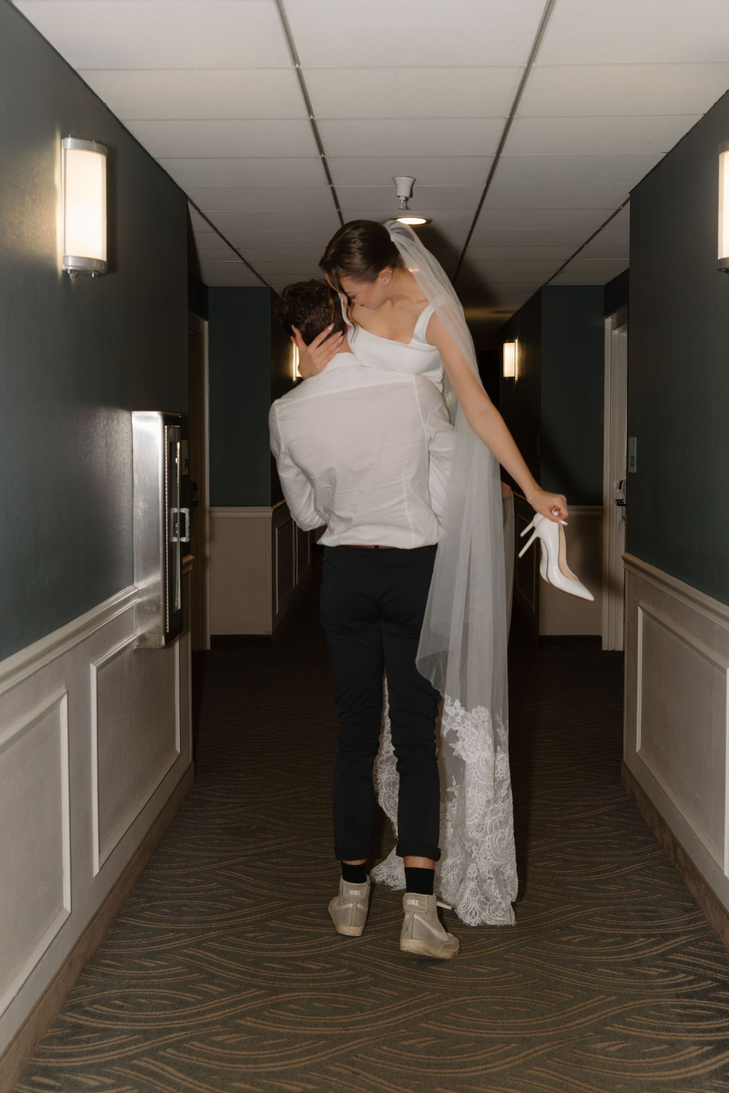 Sequence of photos showing couple walking down dimly lit hotel hallway in playful manner.