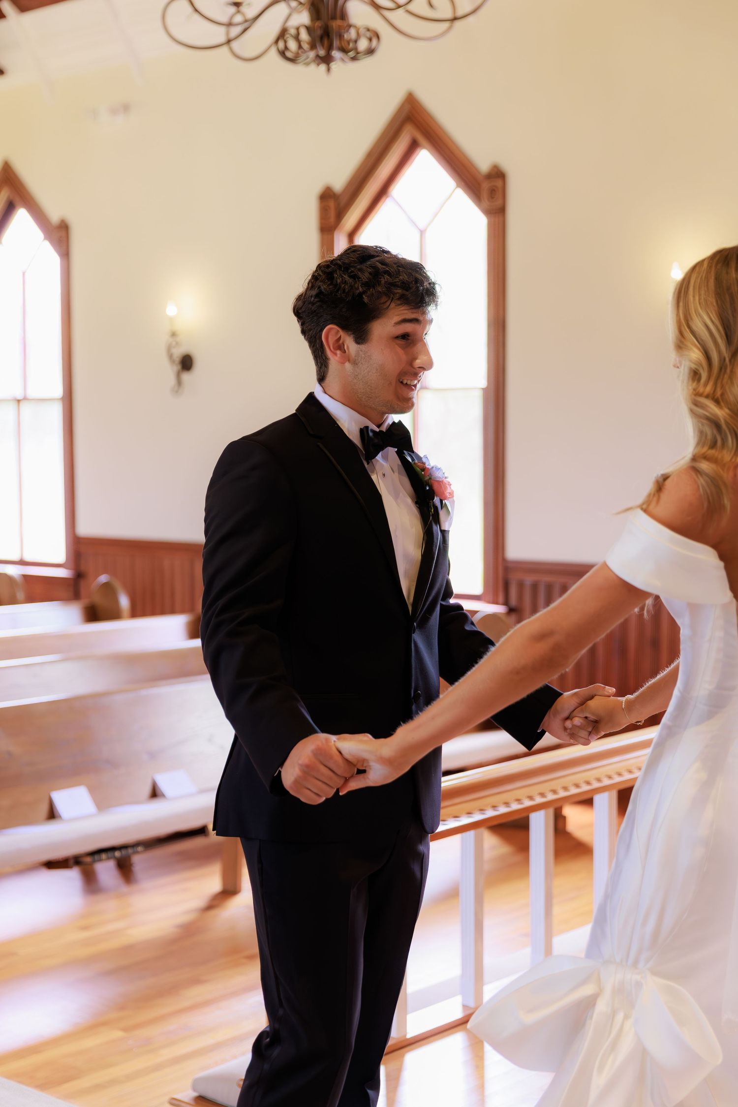 A formal couple interacts in various poses inside a sunlit church with wooden pews.