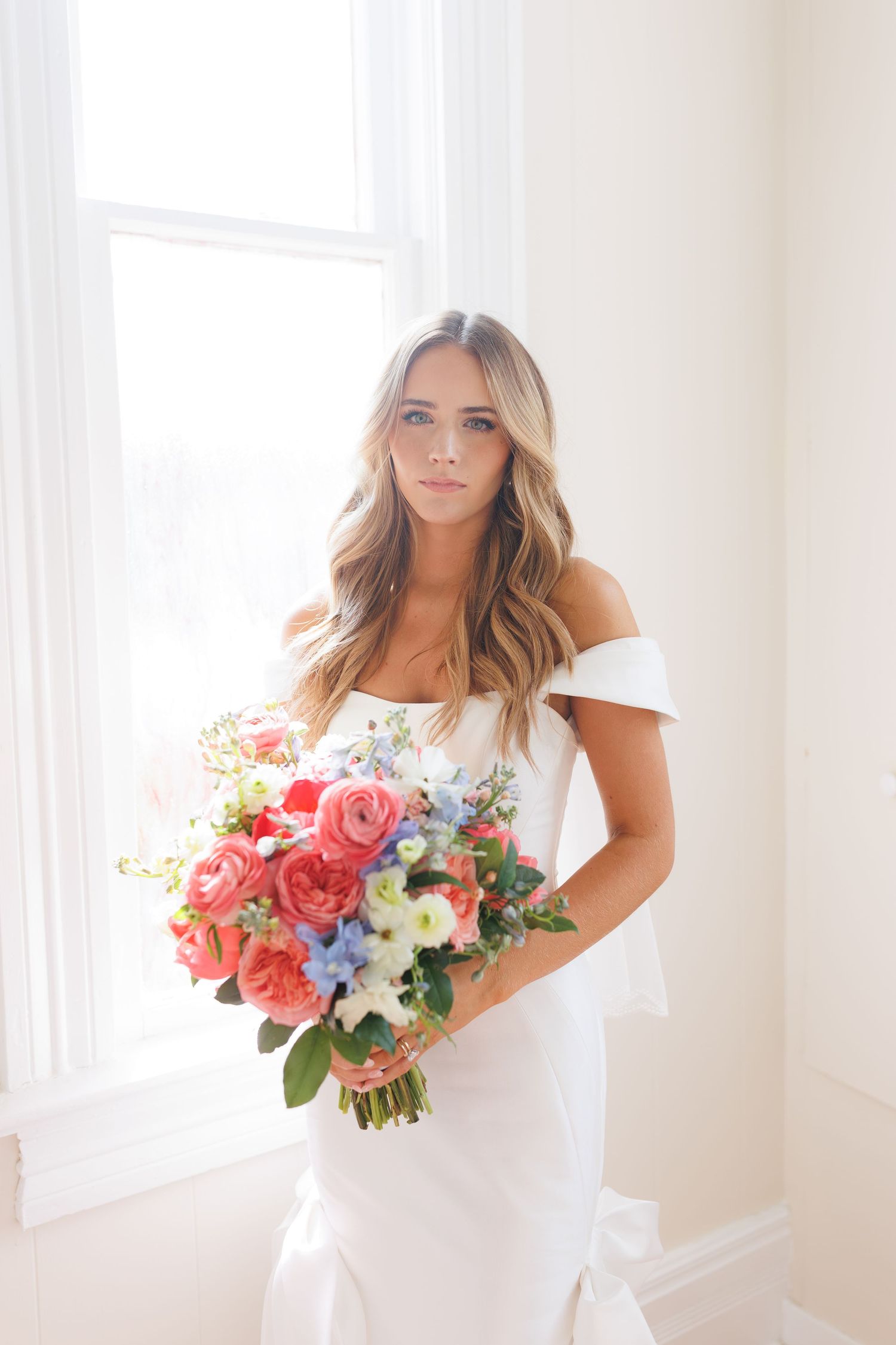 Wedding photos showing elegant white dress and vibrant pink and blue floral bouquet in bright indoor setting.