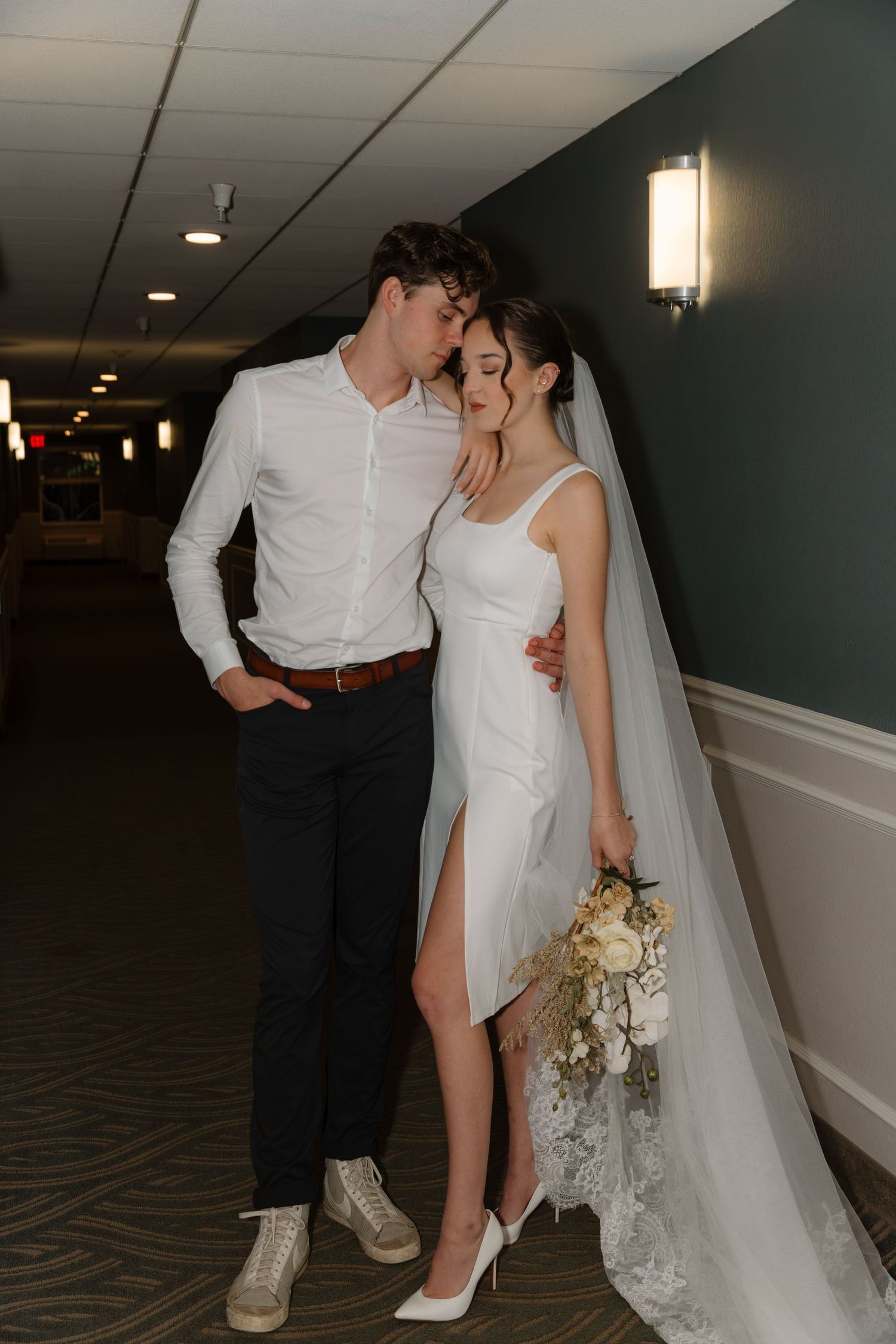 Romantic wedding photo series showing close-up details of couple's shoes and dress in a hotel hallway.