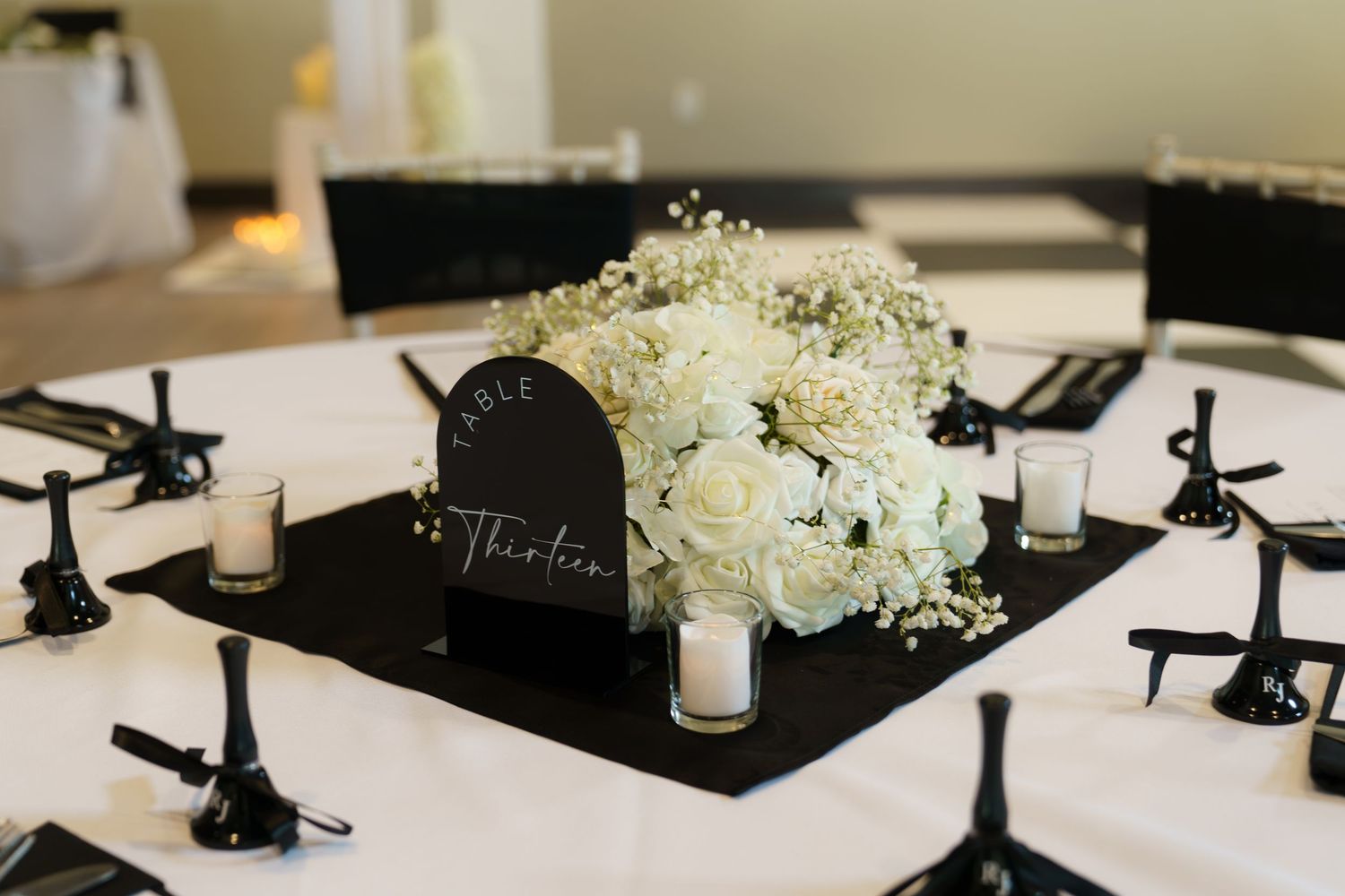 Black candelabras and white floral centerpieces create an elegant table setting for a formal event.