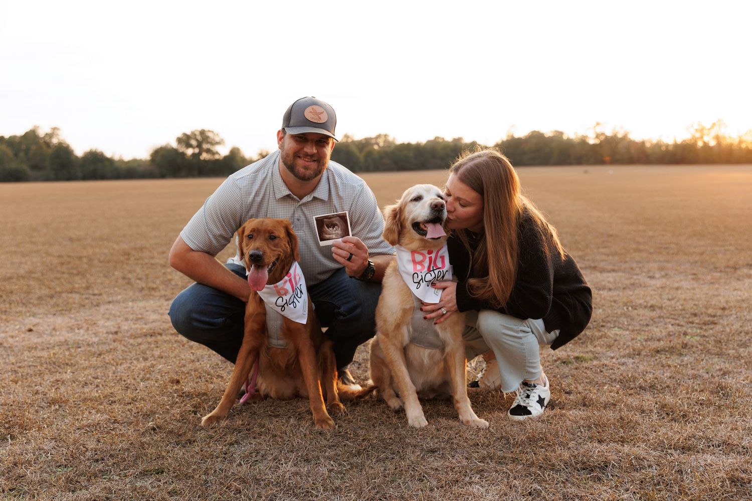 A family and their beagle puppy play together on a sun-dried grass field during golden hour.